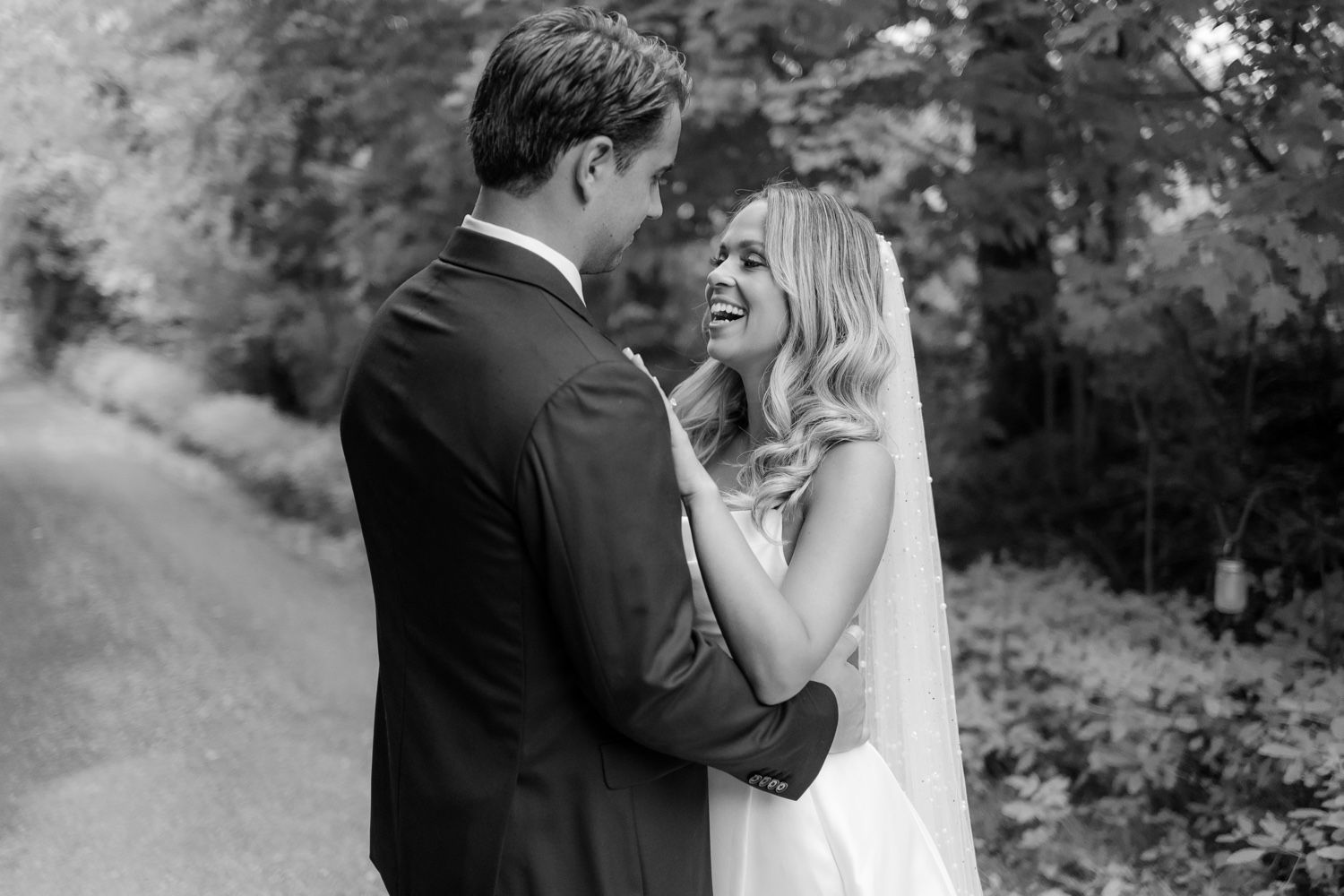 Black and white romantic moment between newlyweds on rustic woodland path.