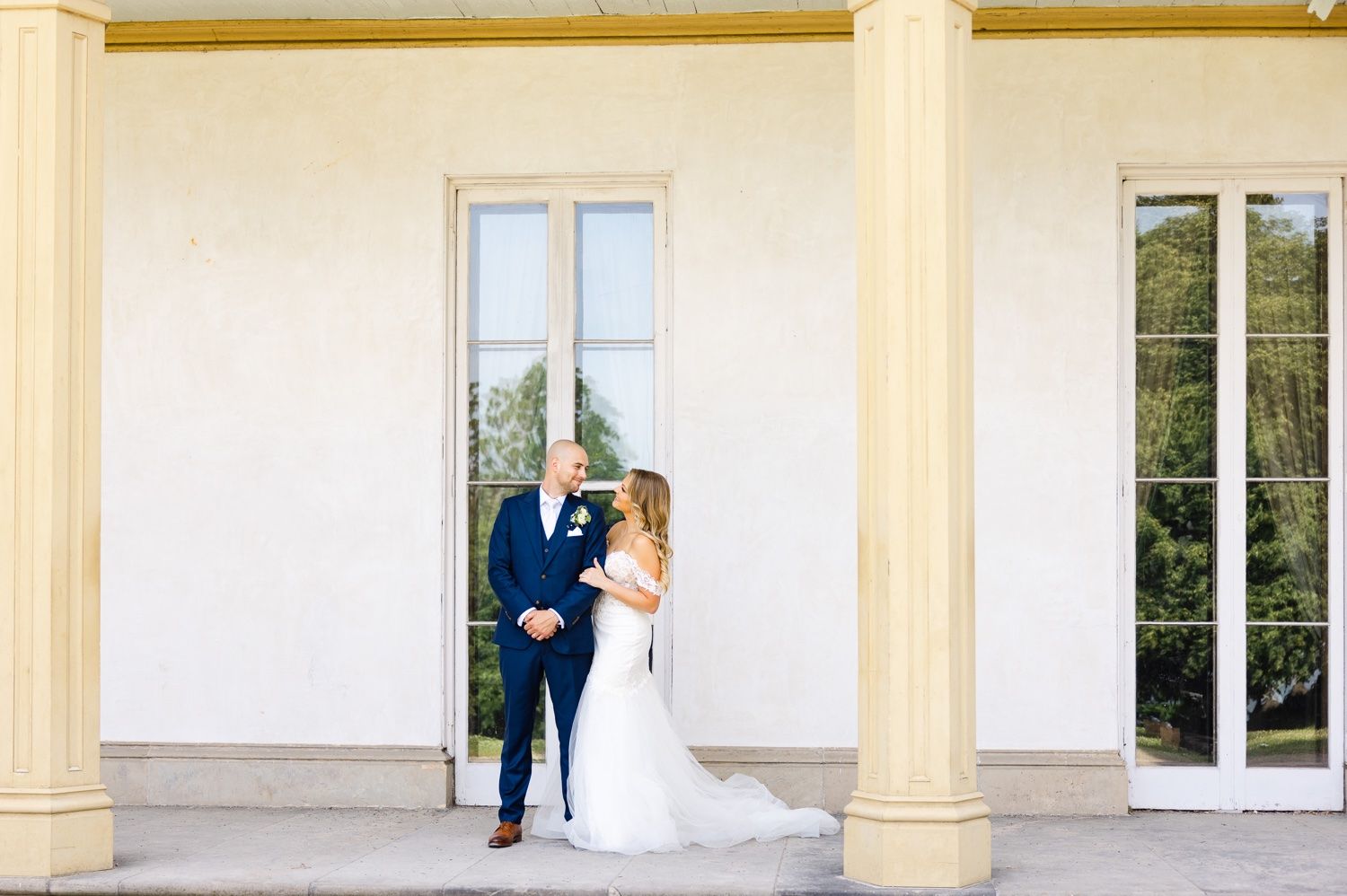 An architectural wedding portrait with tall columns and windows creating an elegant backdrop.