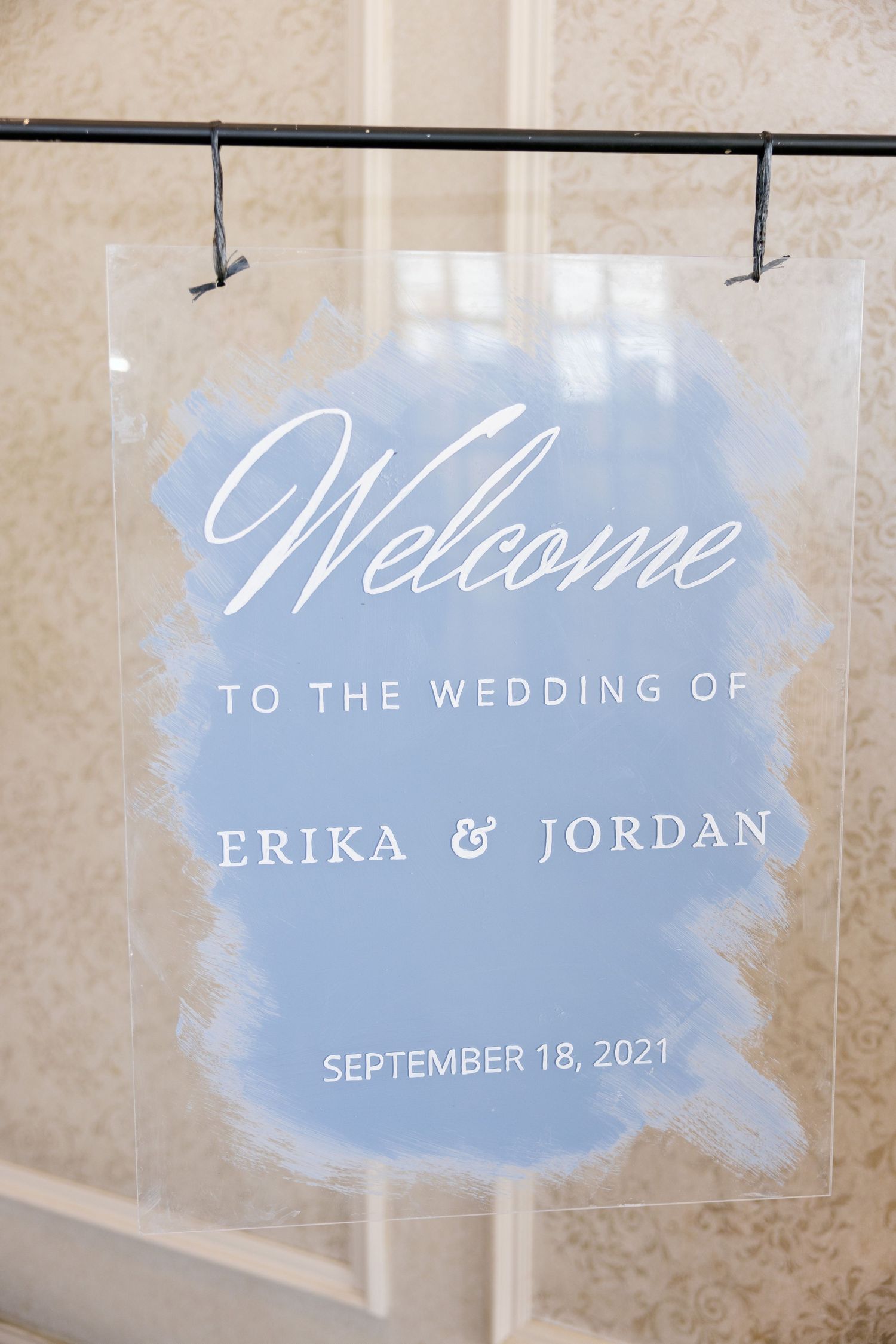 Welcome sign with blue watercolor design announces wedding date on clear acrylic.
