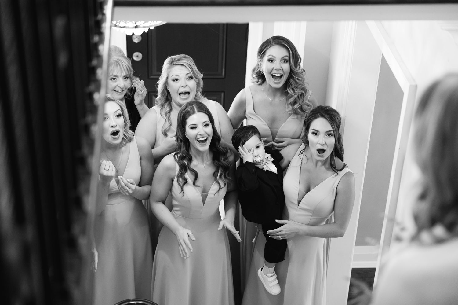 A joyful wedding party moment captured in black and white as they laugh together.