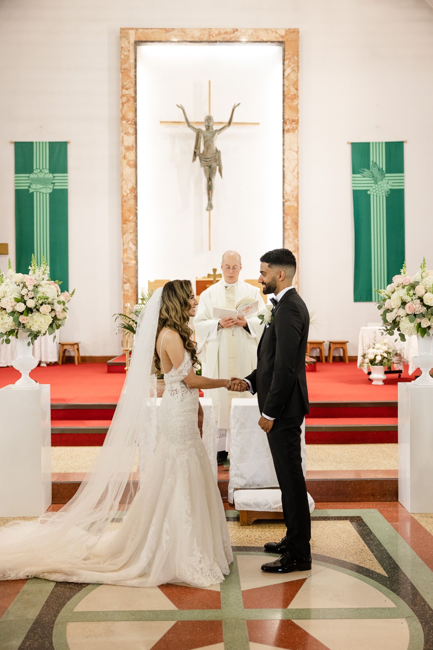 A traditional church wedding ceremony with green banners and white floral arrangements on display.