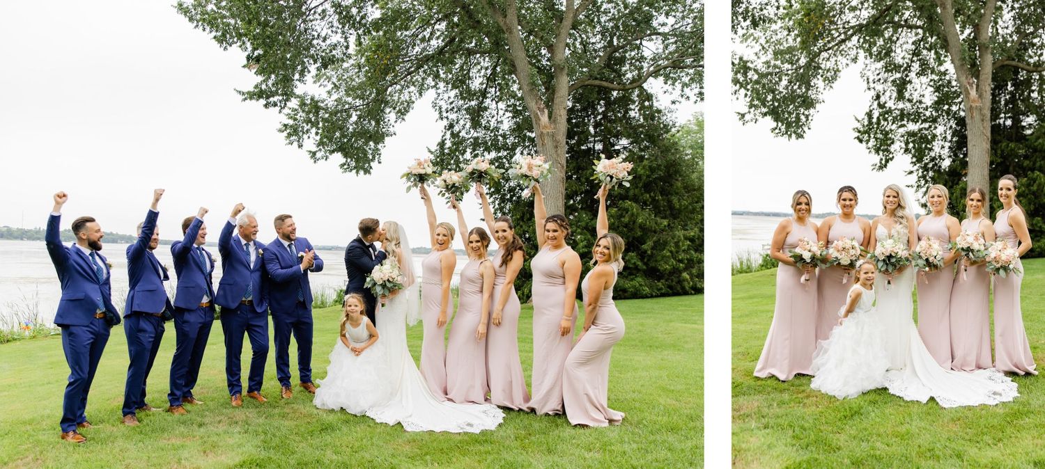 Wedding party celebrates with fun poses on lawn overlooking water.
