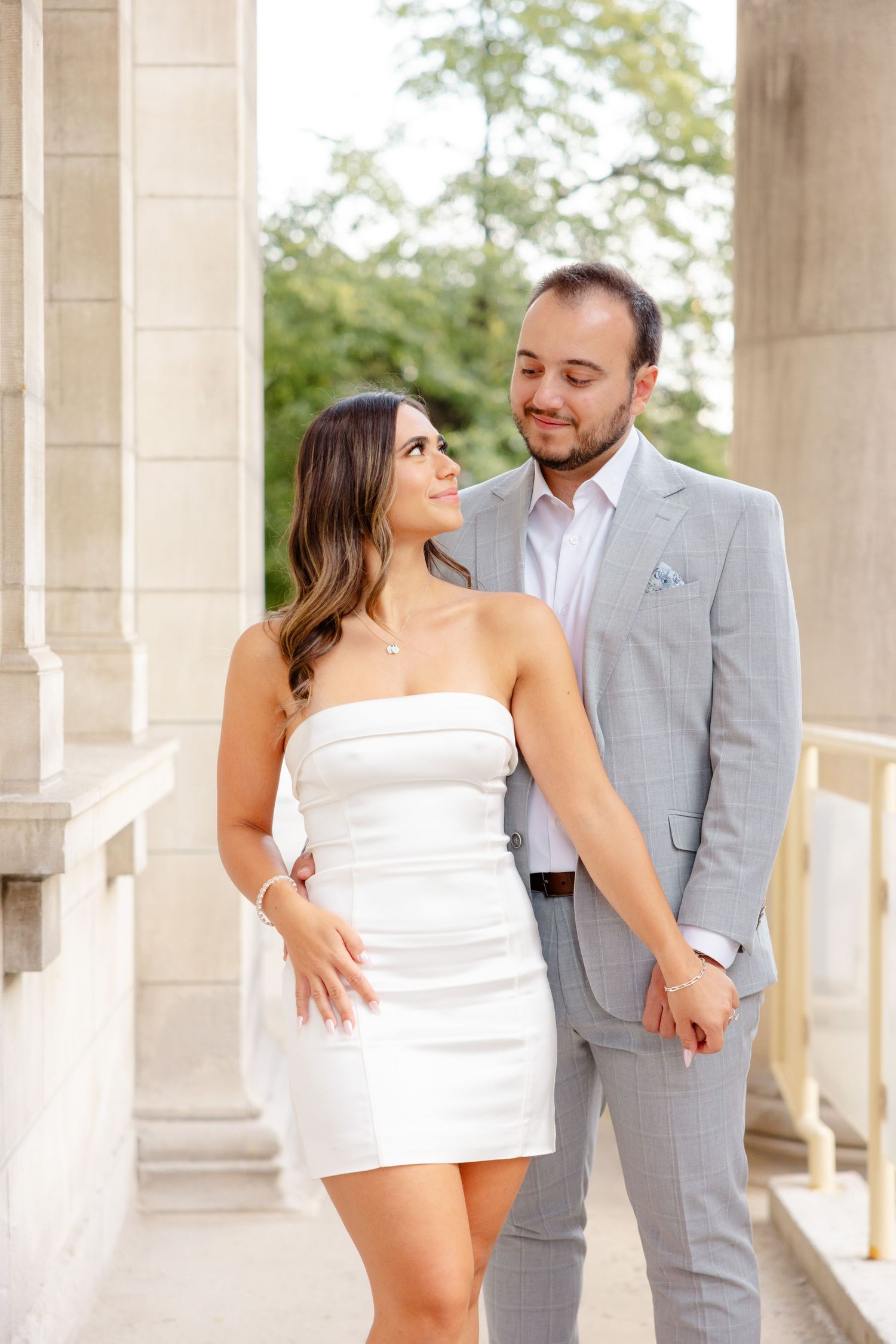 Couple shares an intimate moment while posing between elegant stone columns.