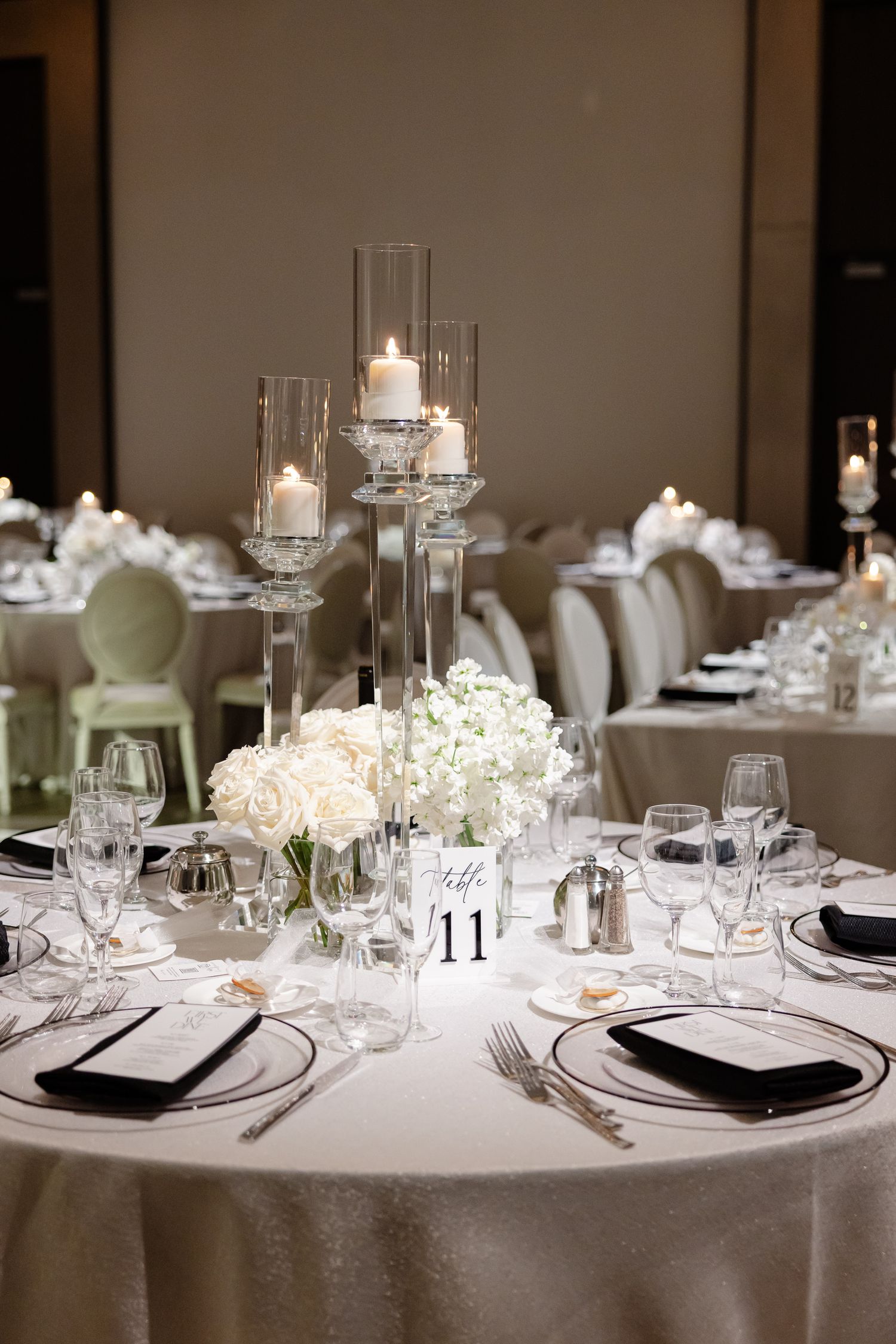 Elegant wedding table setting with white linens, glassware, and candlelight creating a romantic atmosphere.