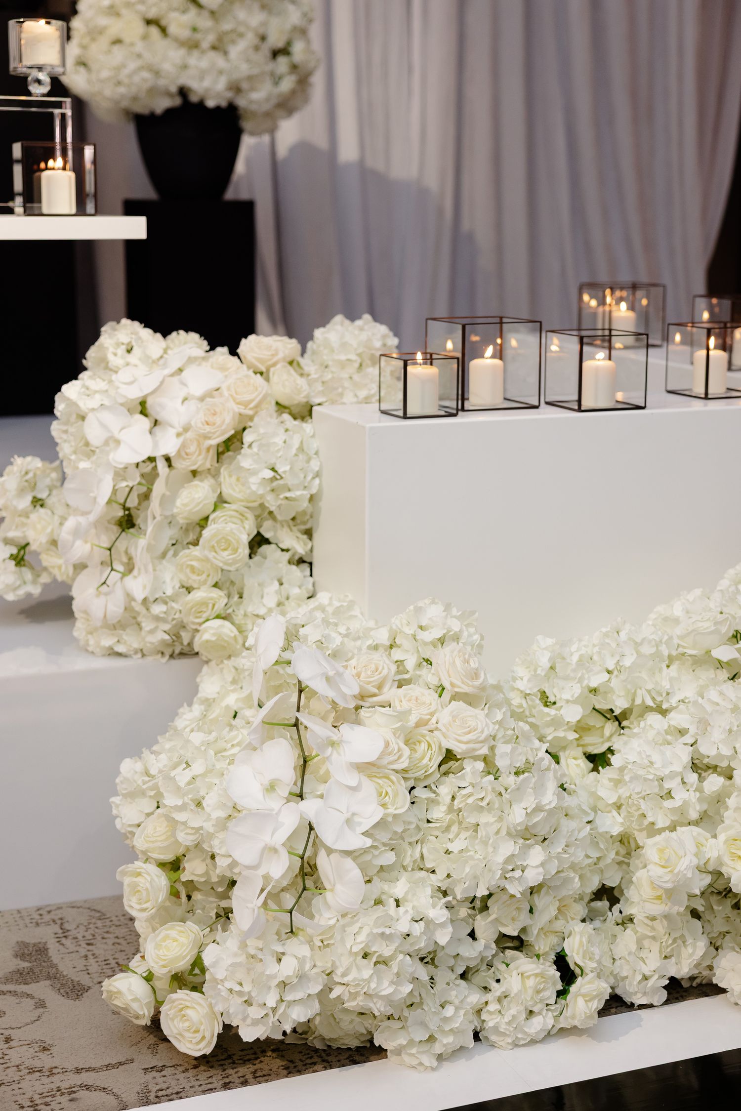 White hydrangea floral arrangements and glass candle holders create an elegant modern wedding decor display.