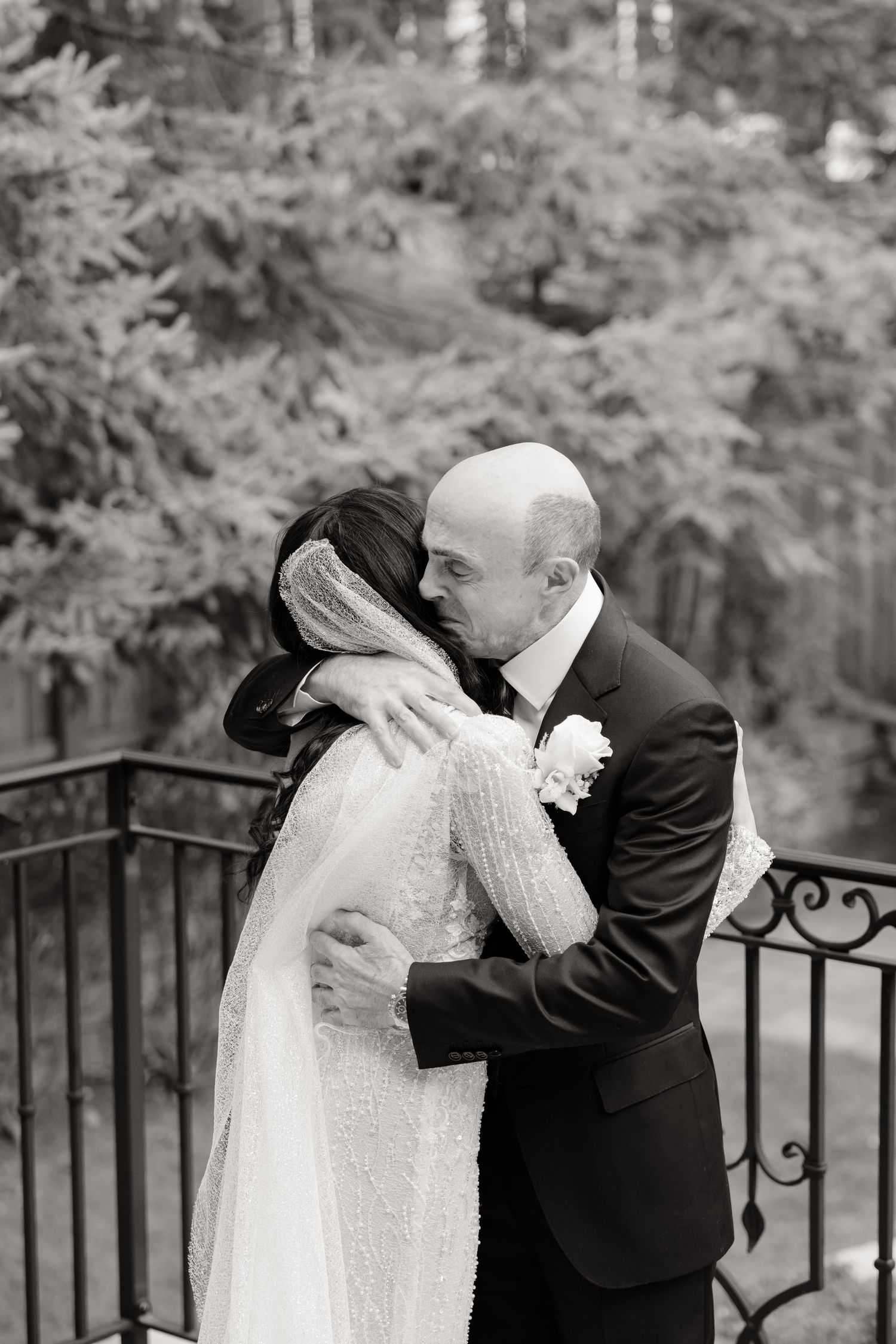 Black and white wedding photo capturing an intimate embrace on a garden terrace.