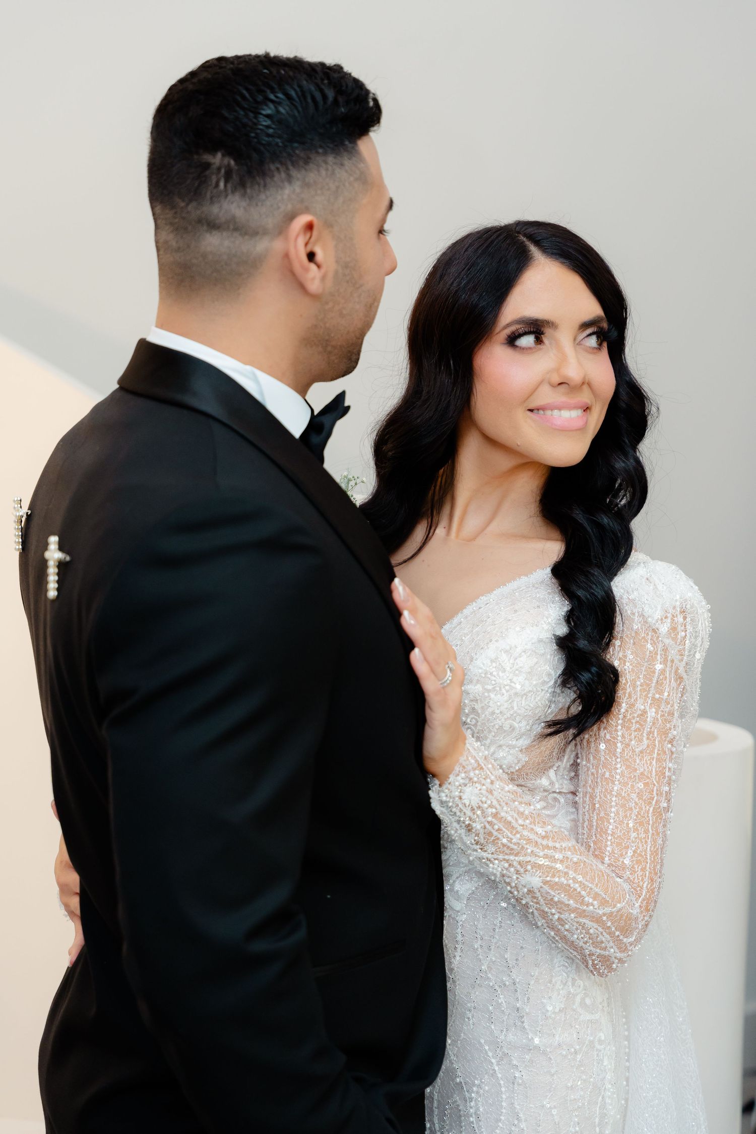 Wedding couple poses in formal attire against a minimalist white background.