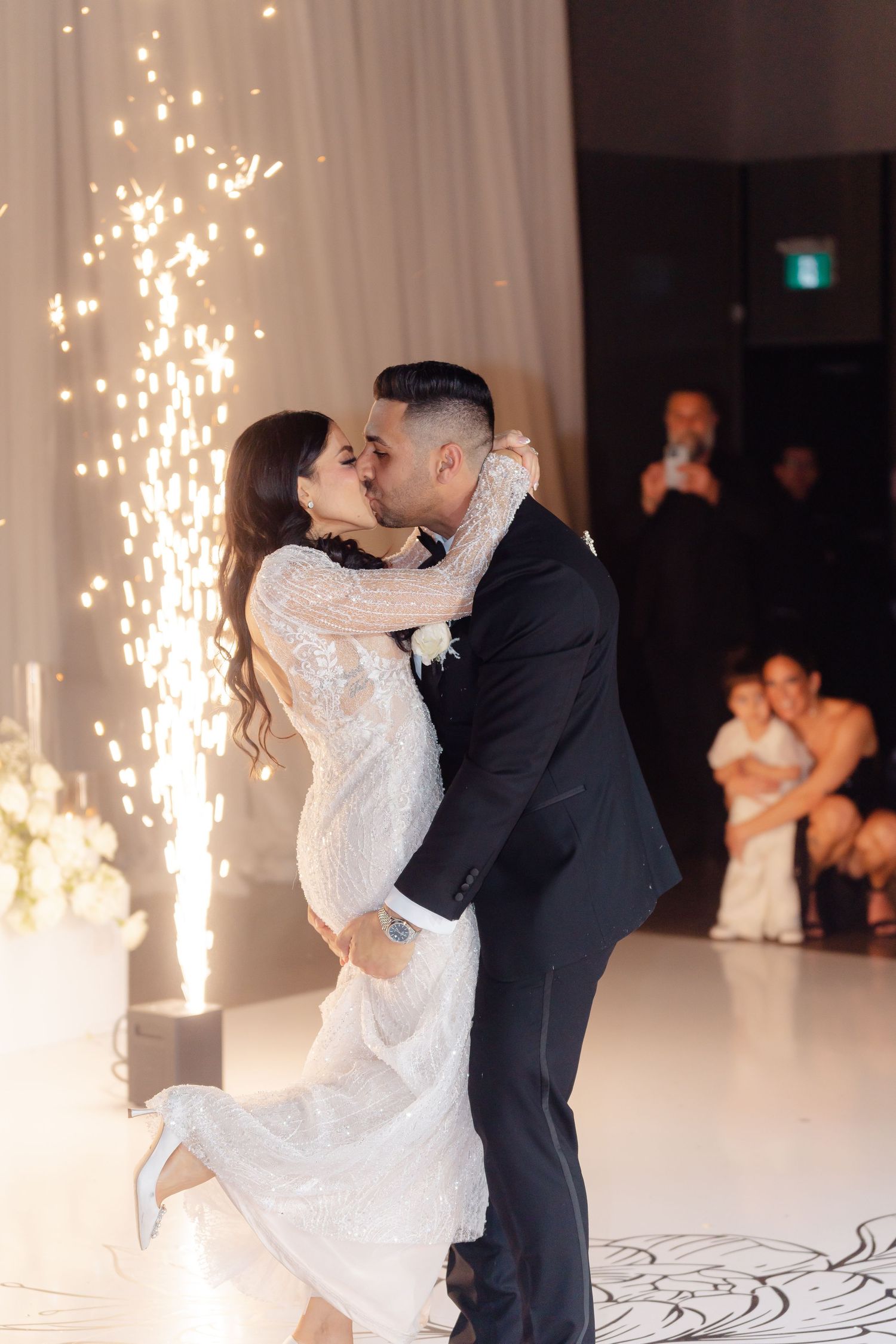 Romantic dance lift with sparklers creating magical backdrop at wedding reception.