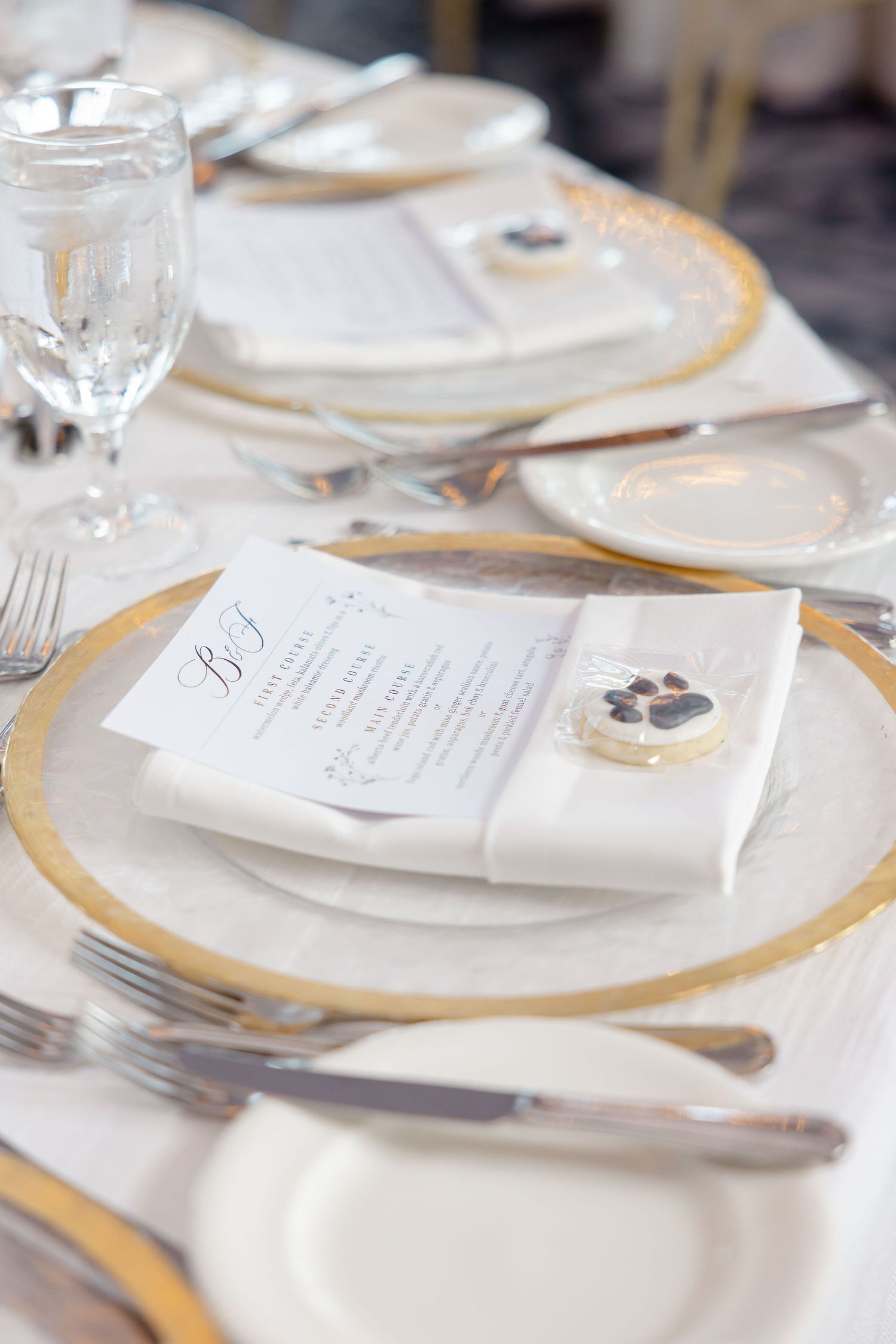 Elegant table setting with gold-rimmed plates, silverware and menu cards for a formal dining event.
