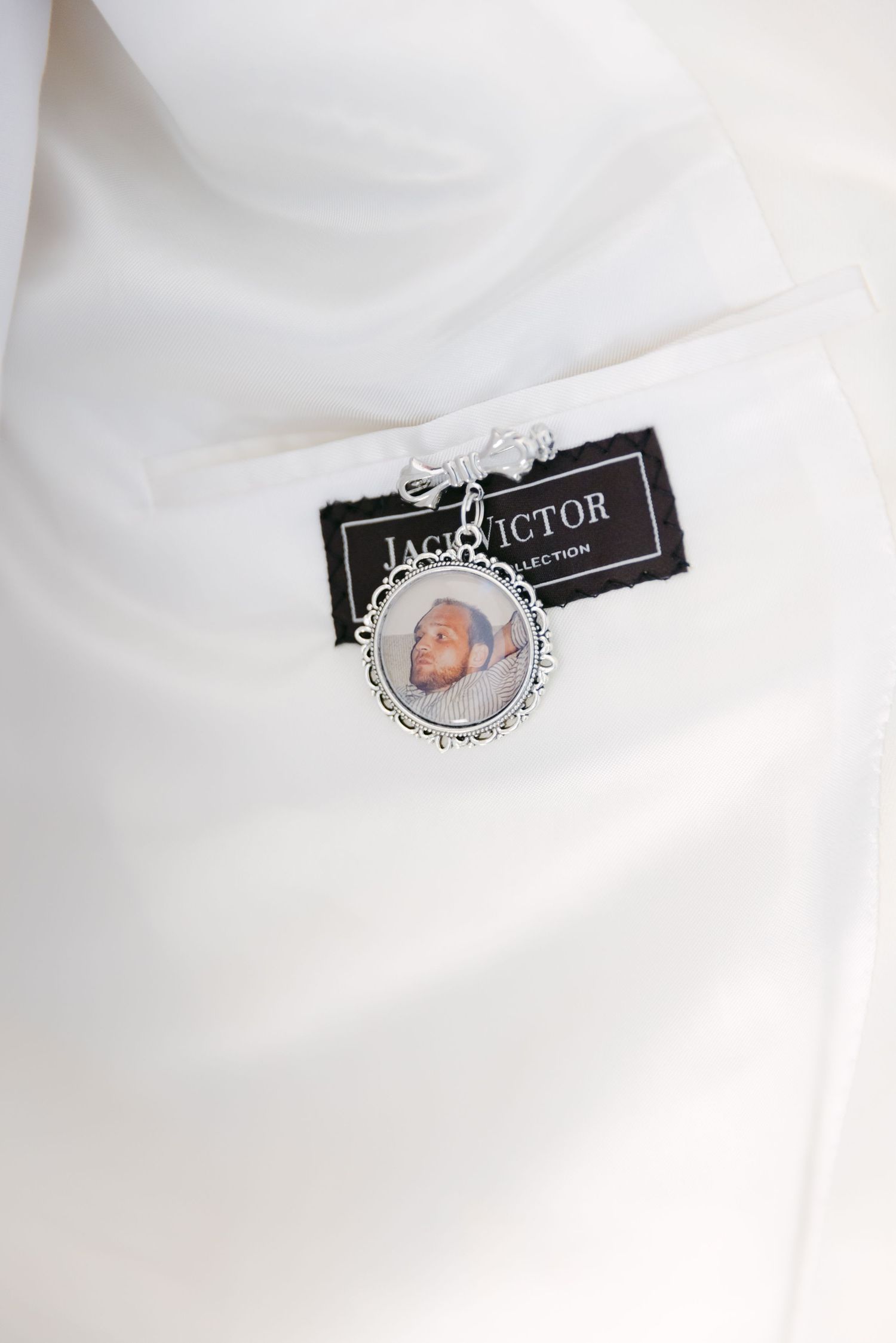 A sentimental photo charm with black tag attached to white fabric.