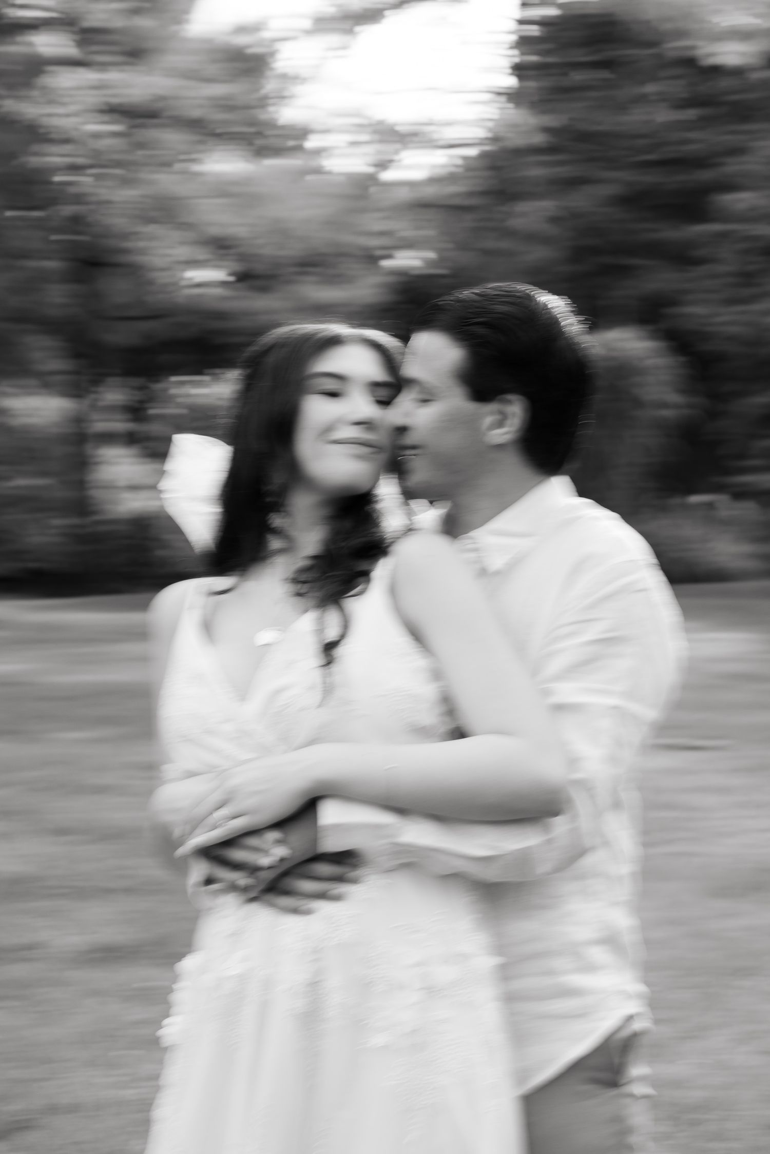Black and white artistic portrait of couple sharing intimate moment in garden setting.