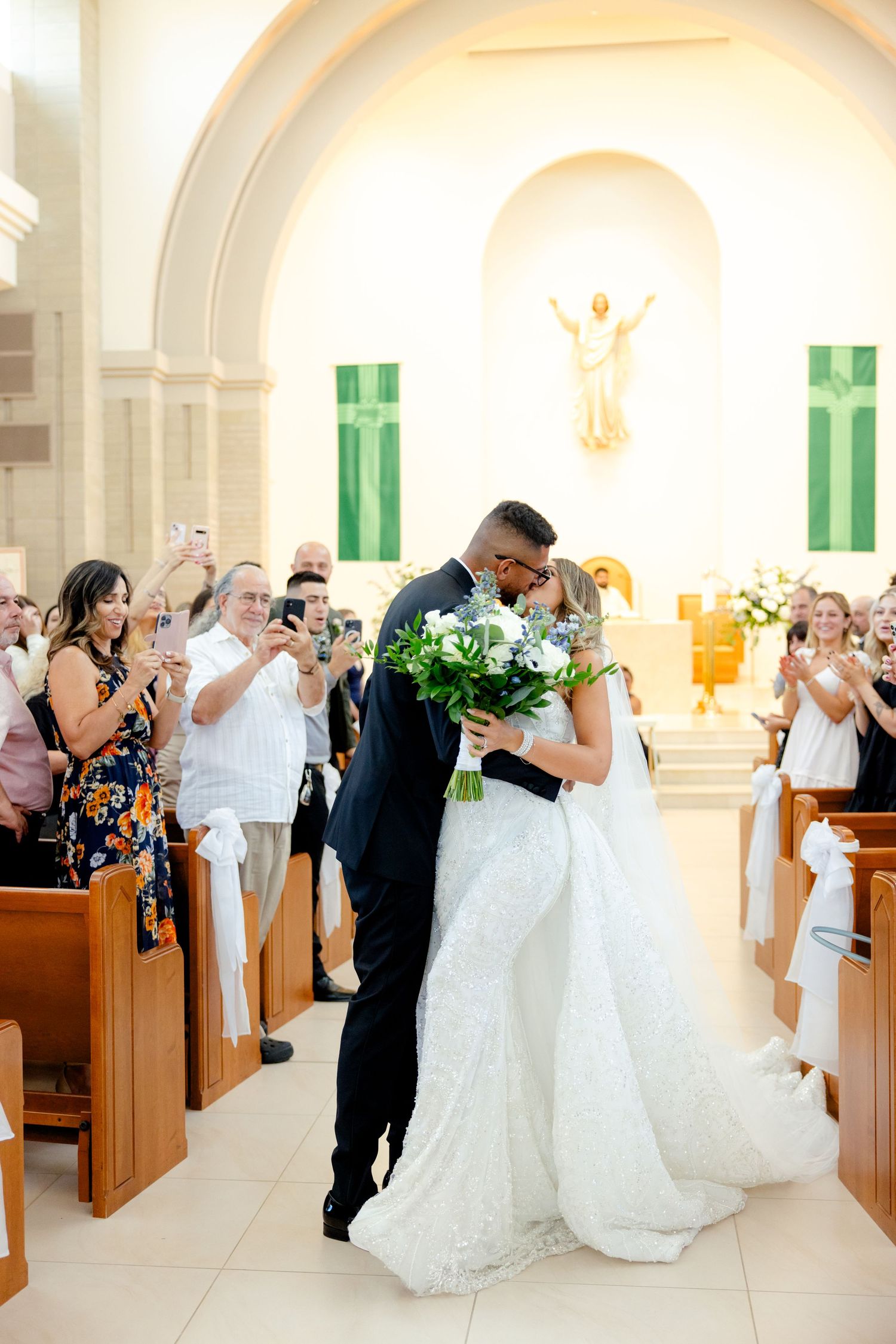 Romantic moment during church wedding recessional with guests applauding.