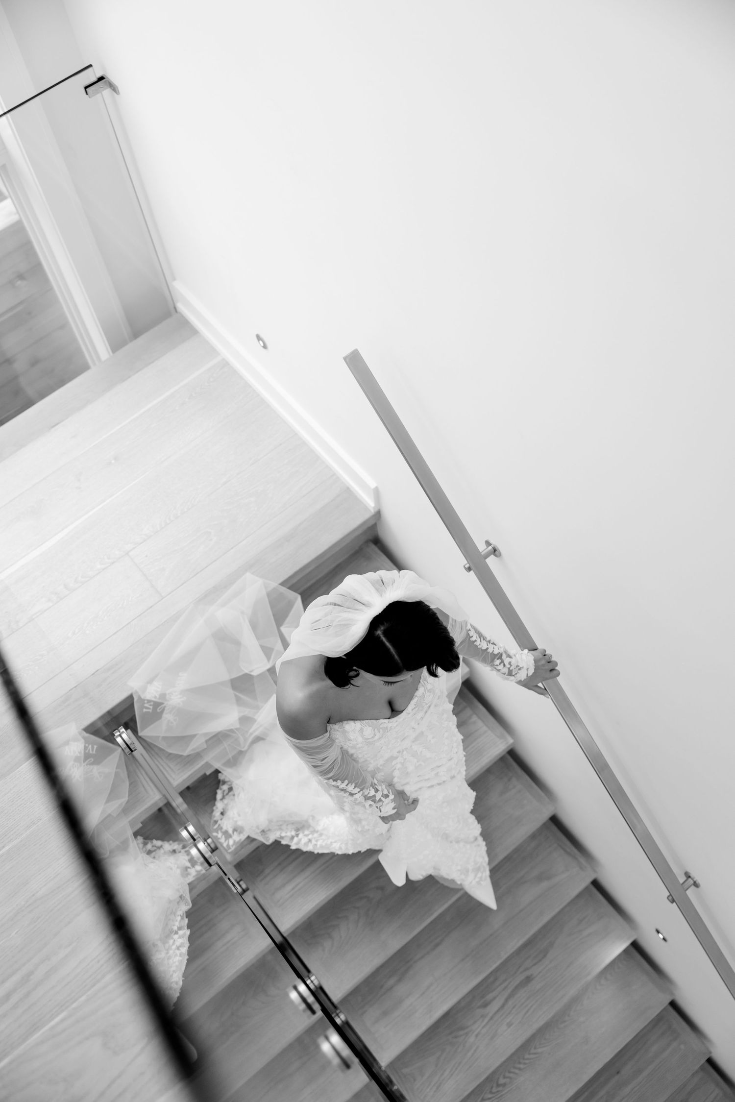 An aerial view of a bride walking down modern stairs in her wedding gown.