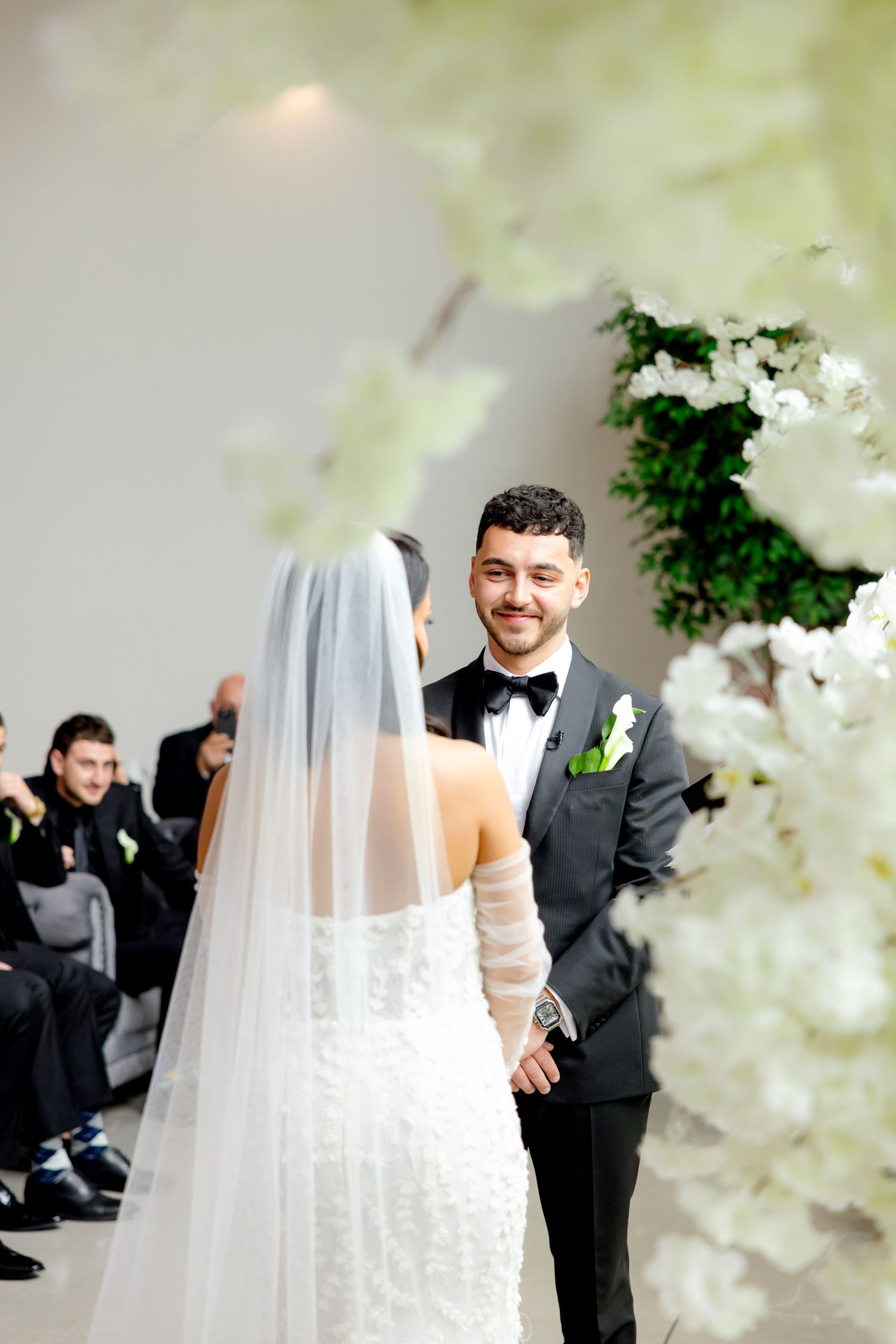 A joyful wedding ceremony moment captured beneath elegant white floral decorations.