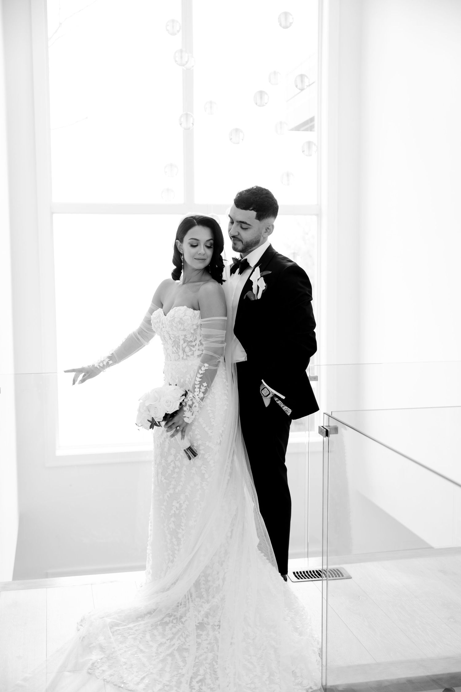 Black and white portrait of wedding couple in elegant pose on staircase.