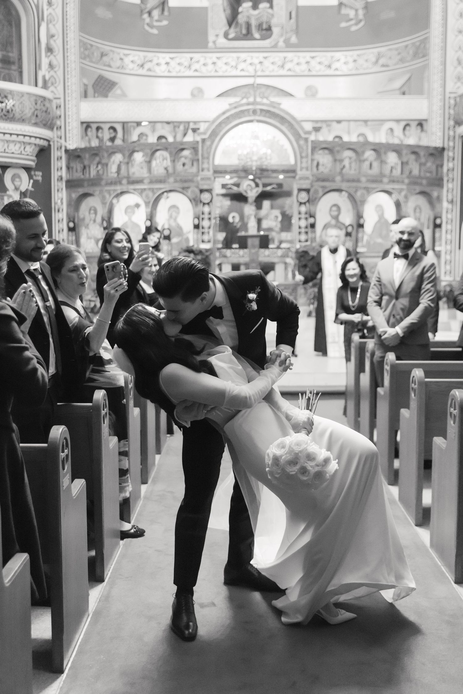 Dramatic black and white photo of romantic dip pose during wedding ceremony in church.