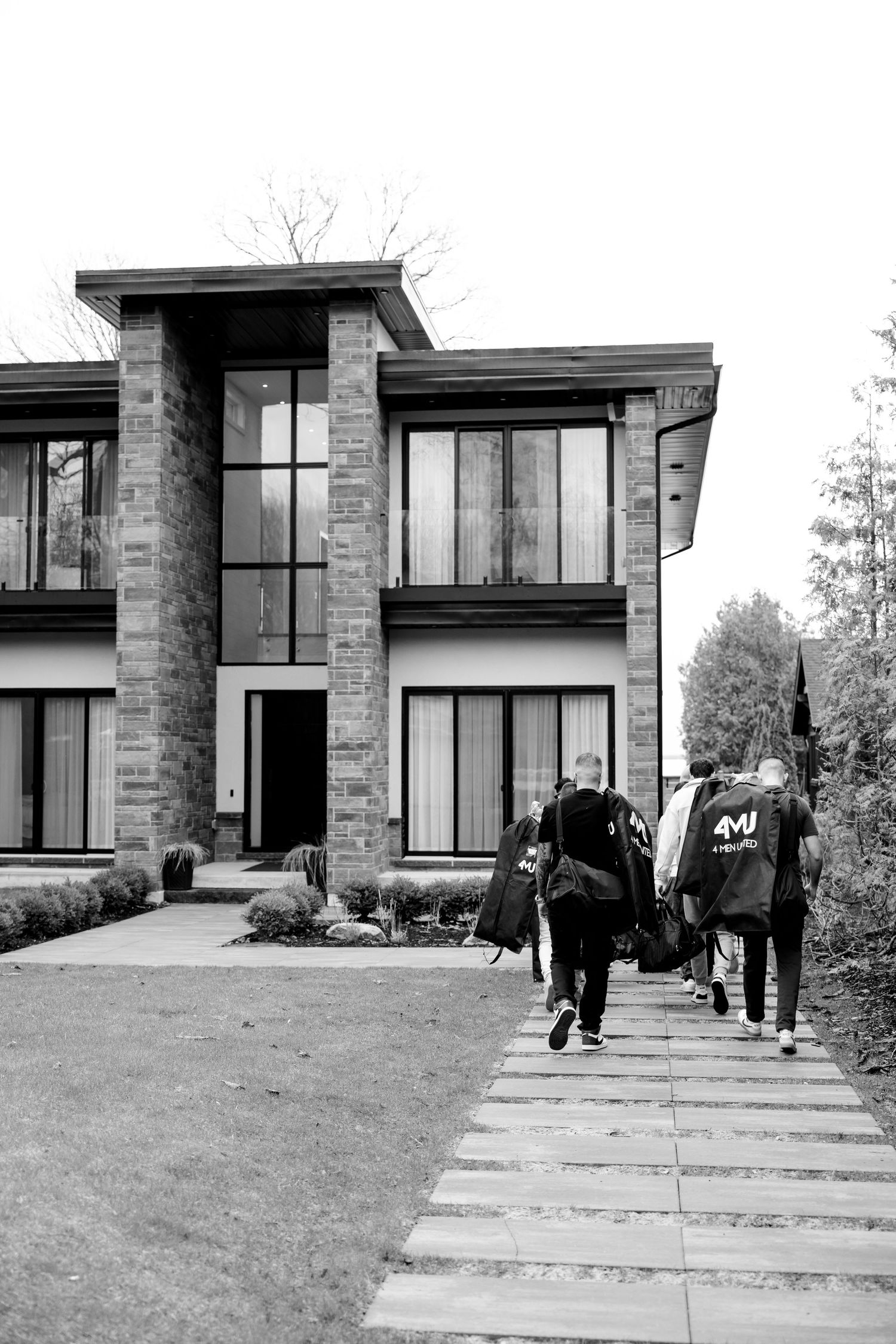 Modern stone and glass house exterior with people walking up pathway.
