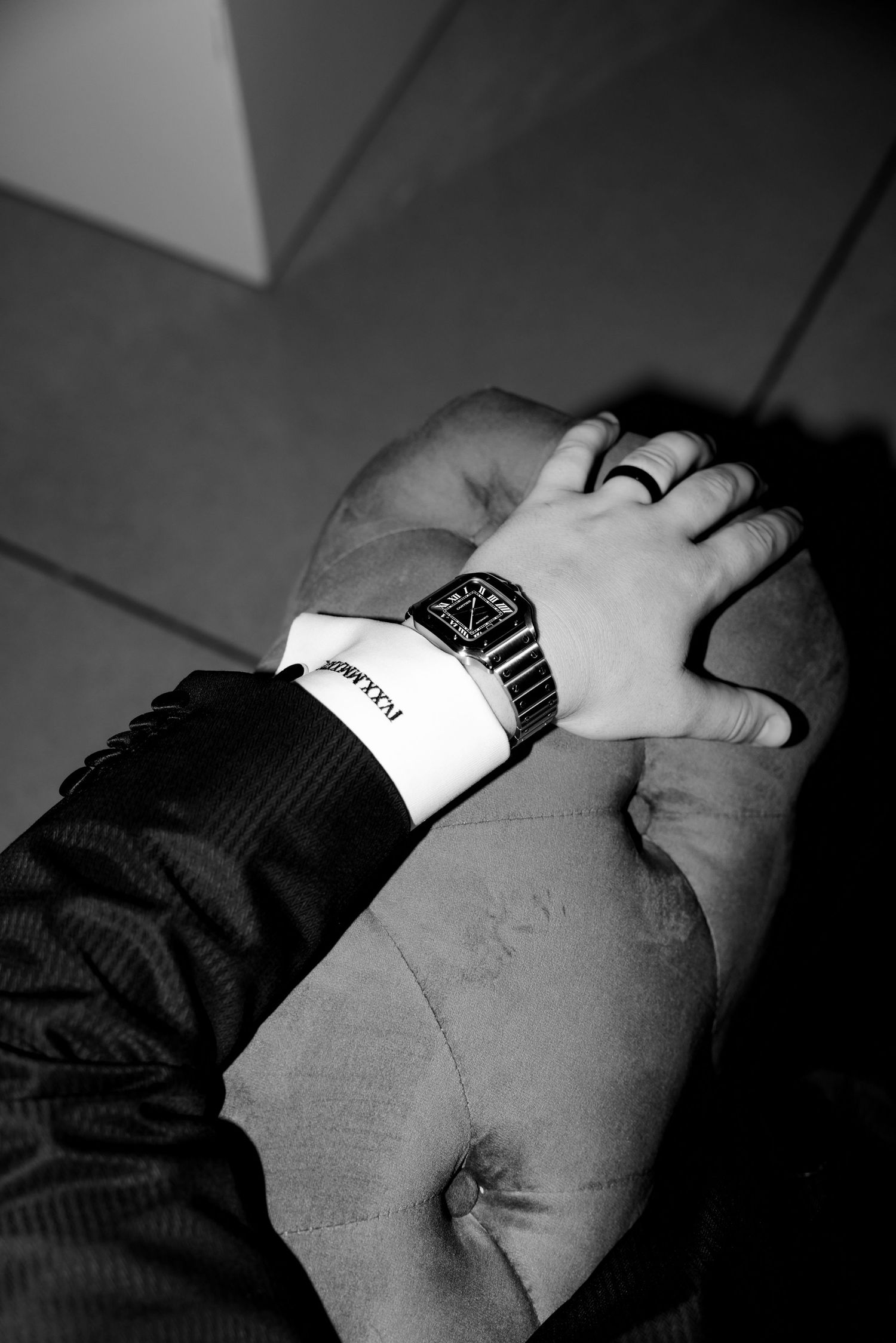 Close-up of formal watch and wedding ring on resting hand in black and white.