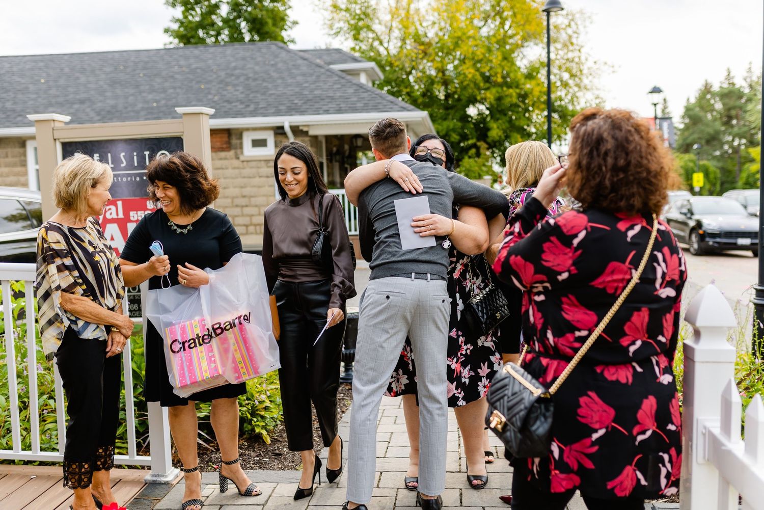 A group of people gathered on a porch during a celebratory event with gift bags.