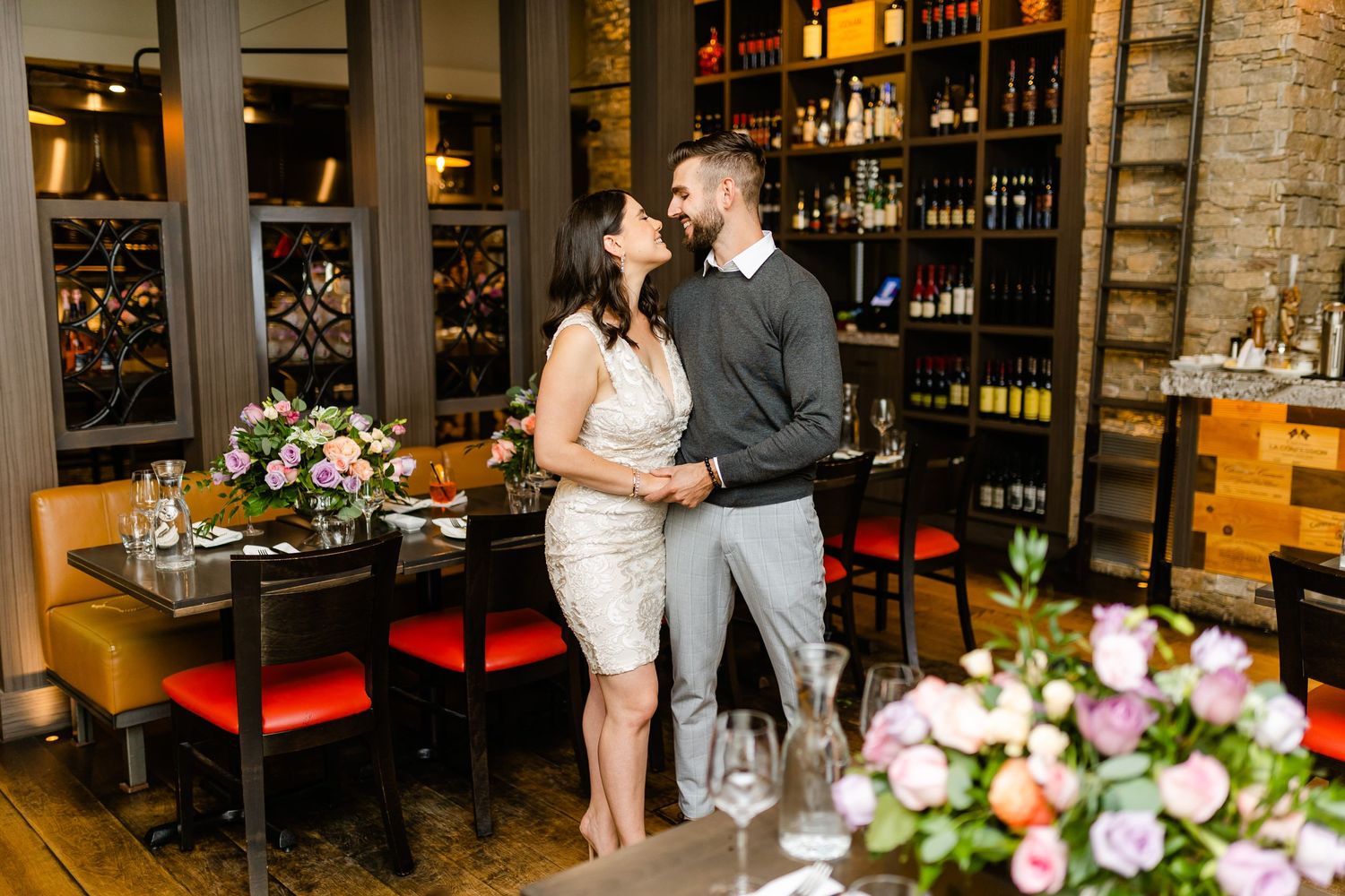 Intimate celebration moment in a rustic wine bar setting with floral decorations.