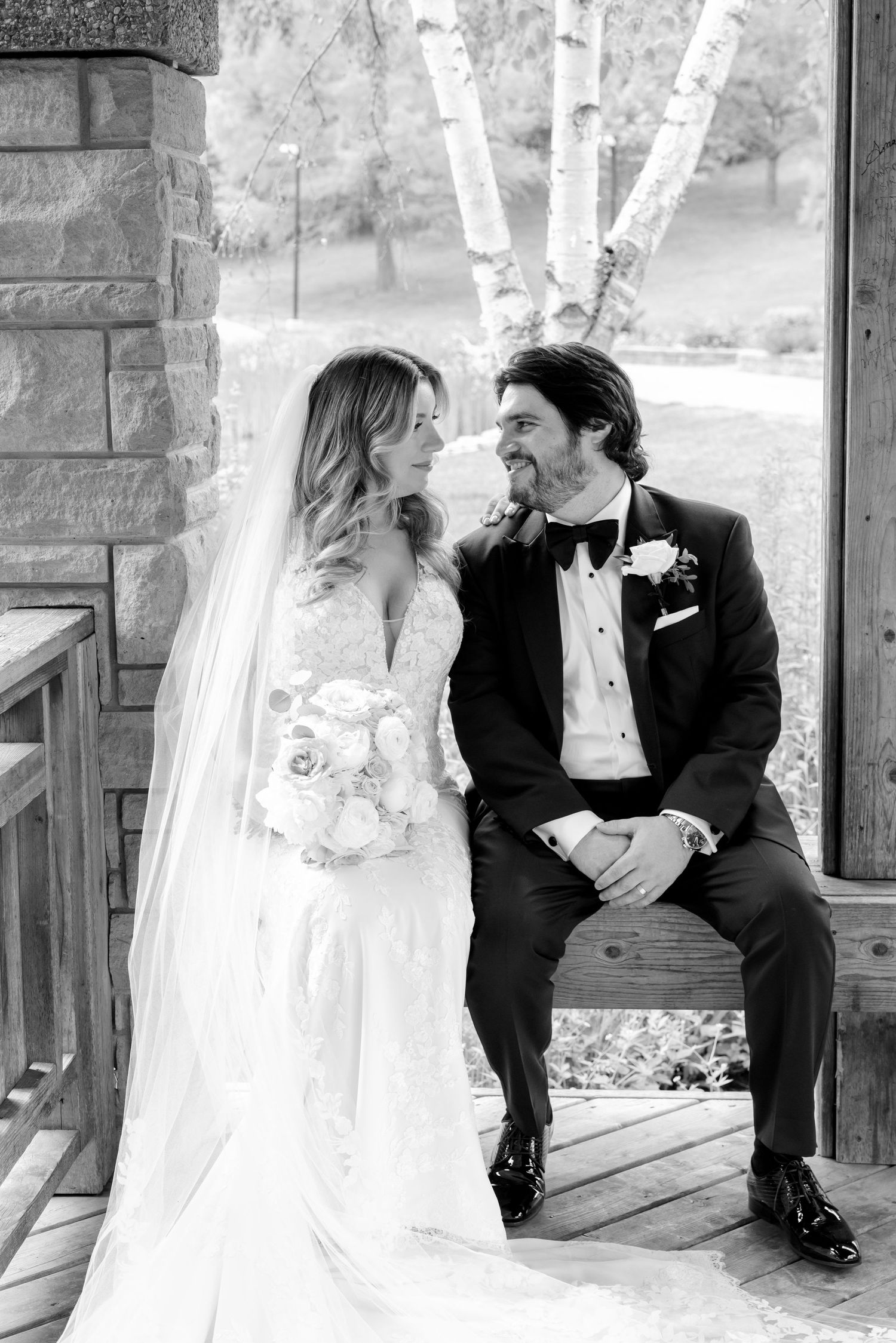 Black and white wedding portrait captured in rustic outdoor pavilion setting.