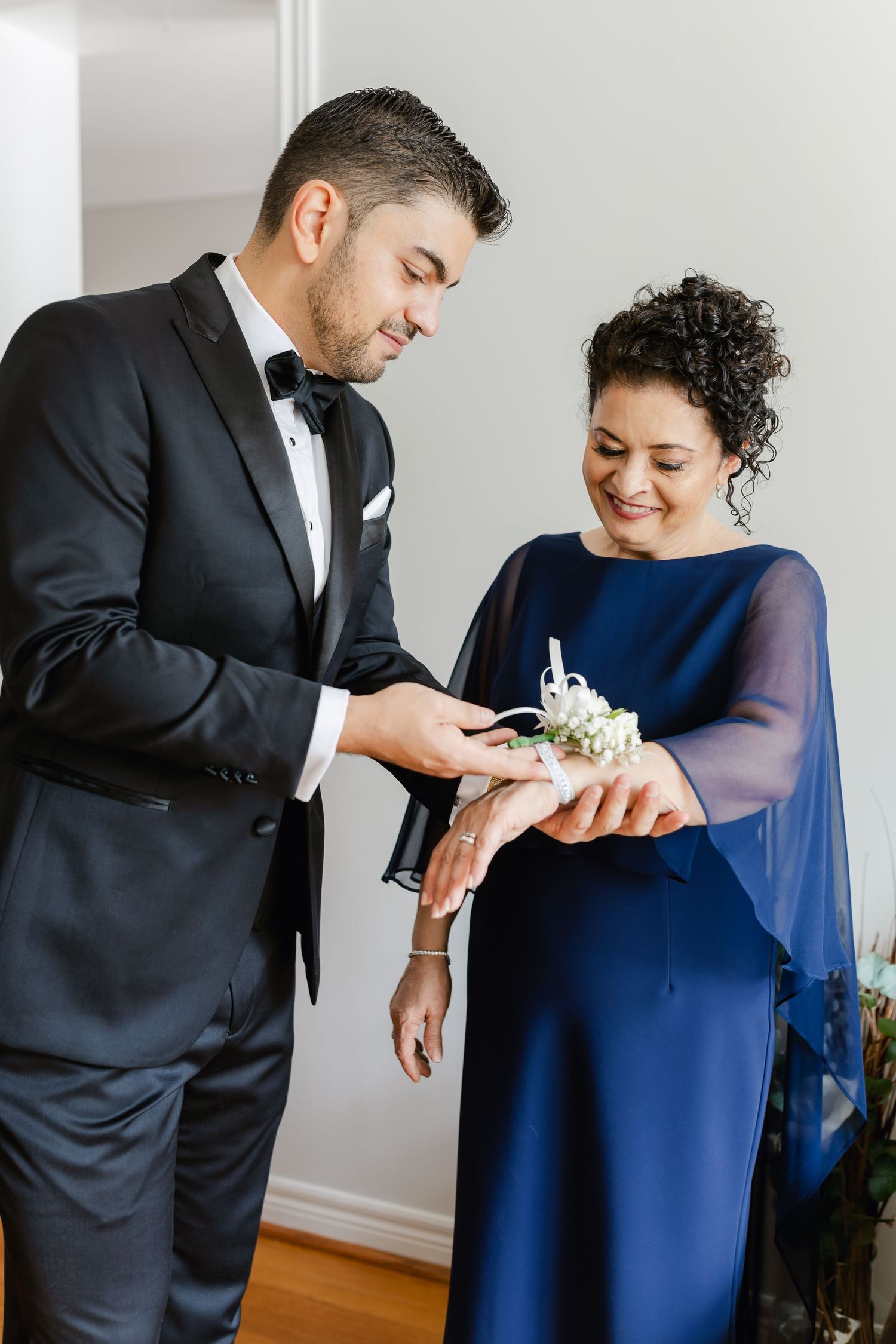 A formal moment captured while pinning a boutonniere on a tuxedo lapel.