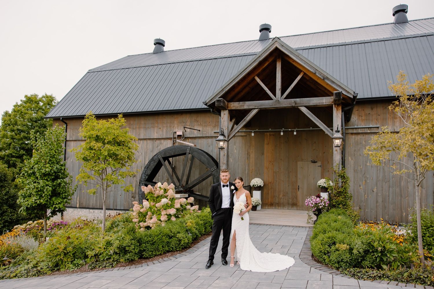Rustic barn wedding venue with metal roof and wooden beams creates romantic backdrop for couple's special moment.