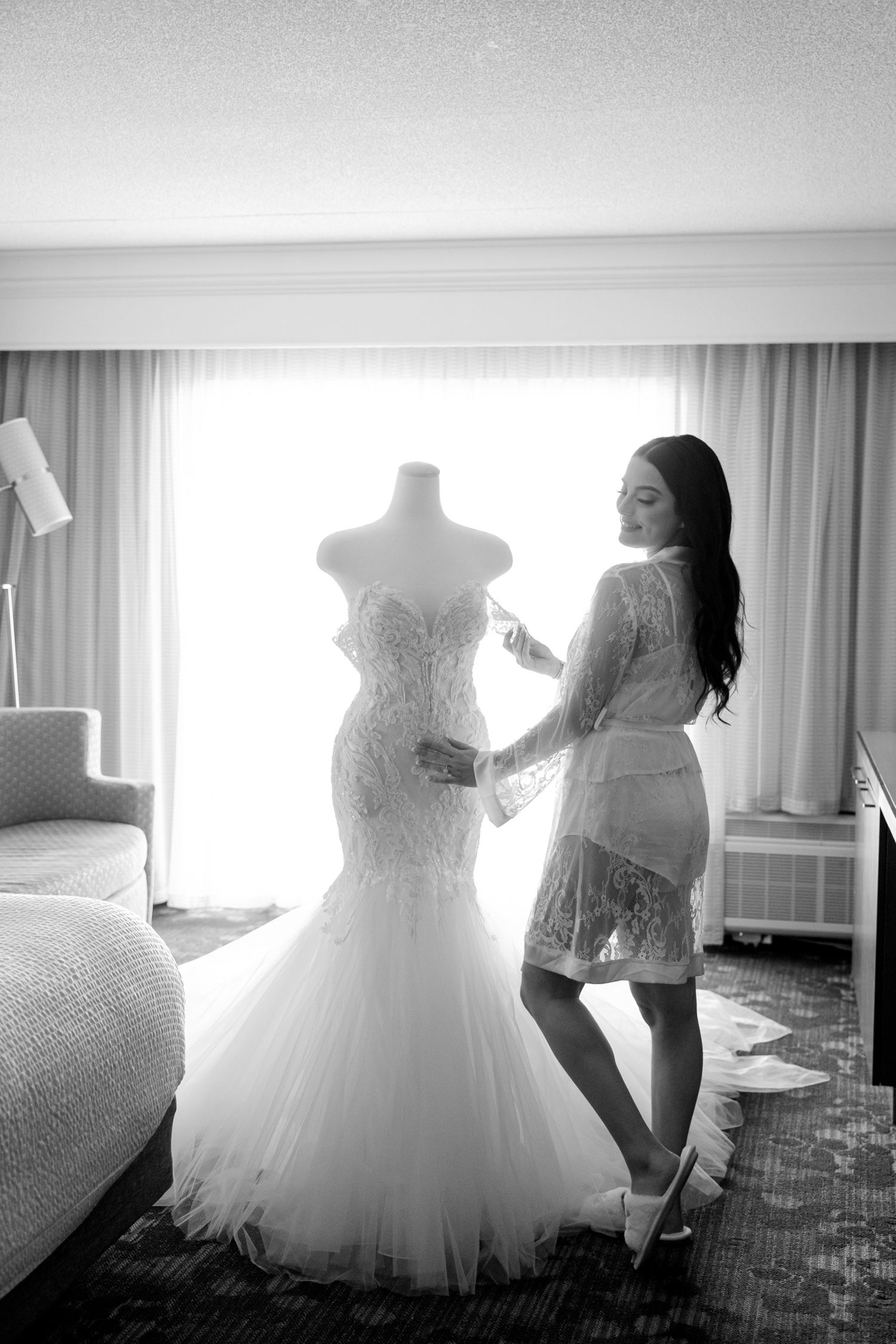 Elegant mermaid wedding gown displayed against bright window light.