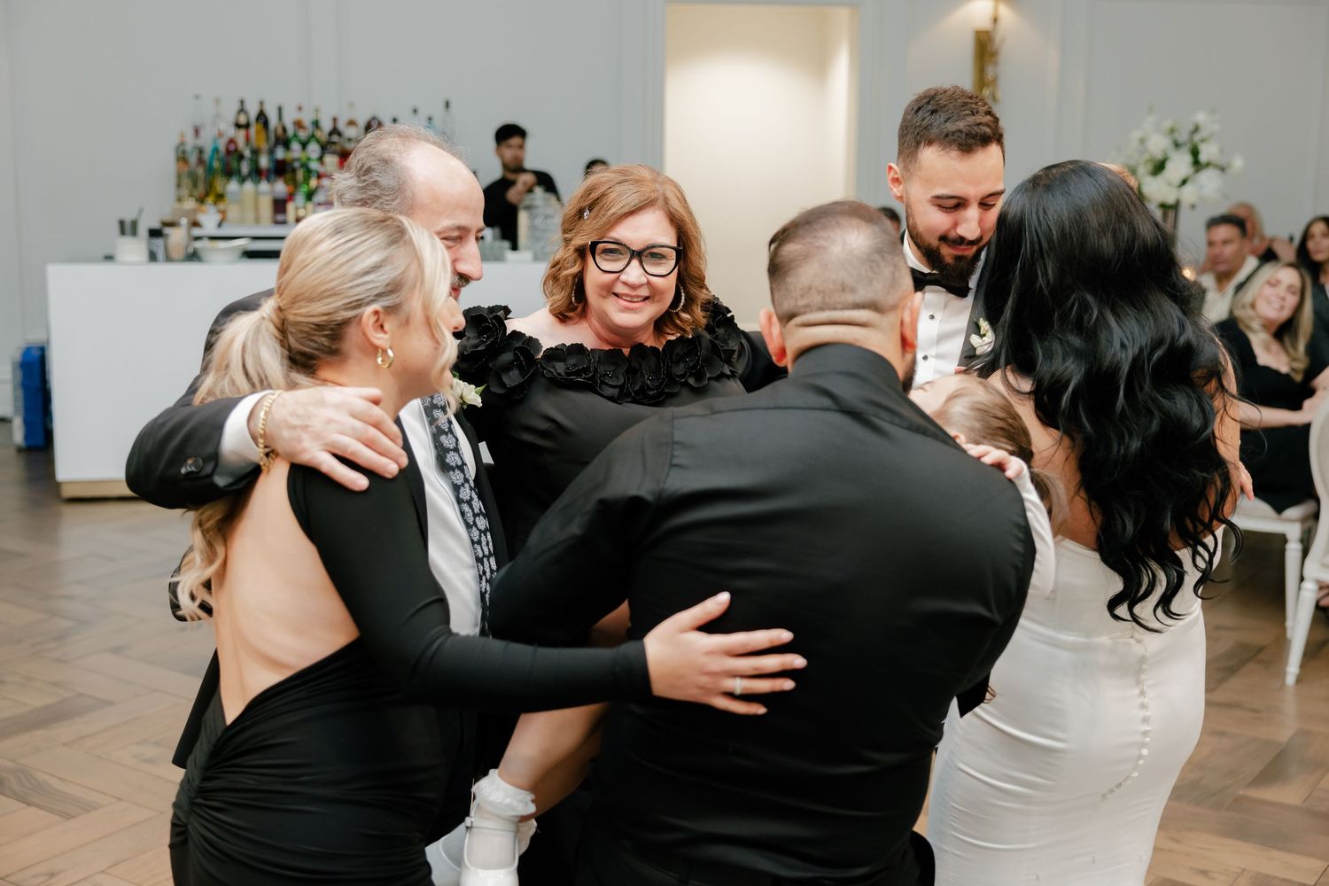 Wedding guests embrace in a celebratory group hug during the reception festivities.