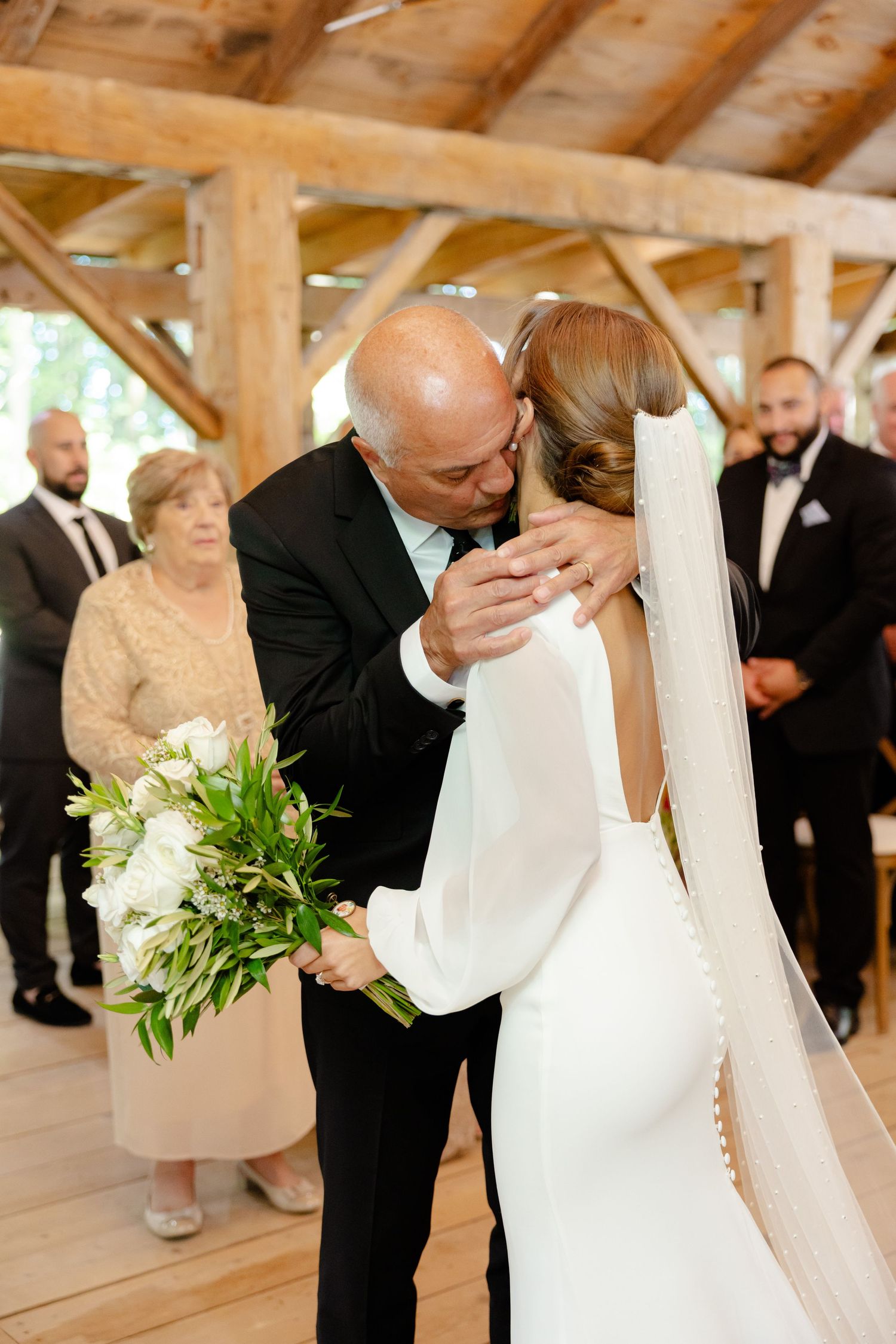 An emotional moment during a wedding ceremony in a rustic wooden barn venue.