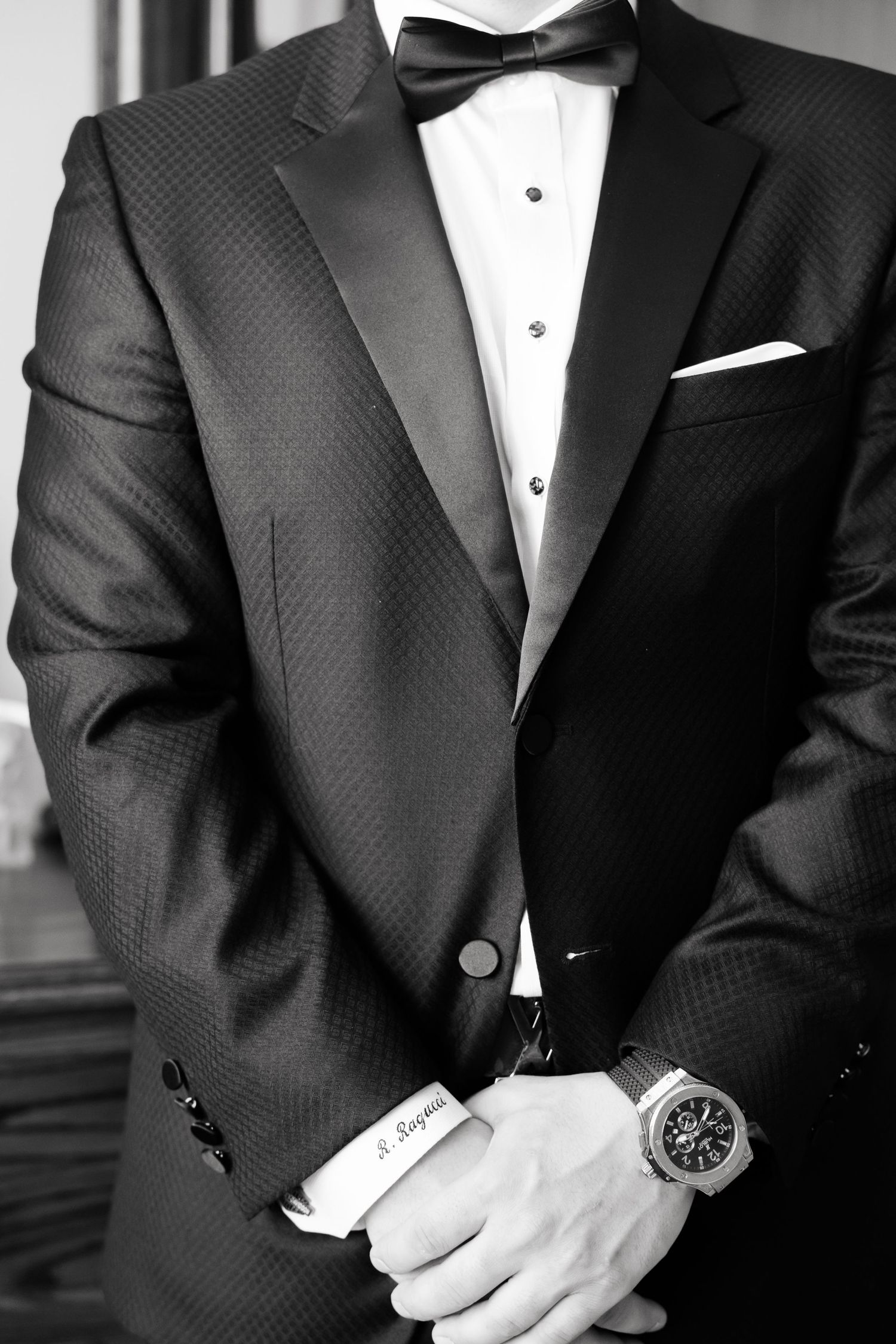 Black and white detail shot of textured tuxedo jacket with bow tie and pocket square.