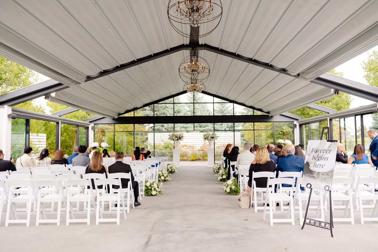 A modern wedding venue setup with white chairs and natural lighting streaming through large windows.