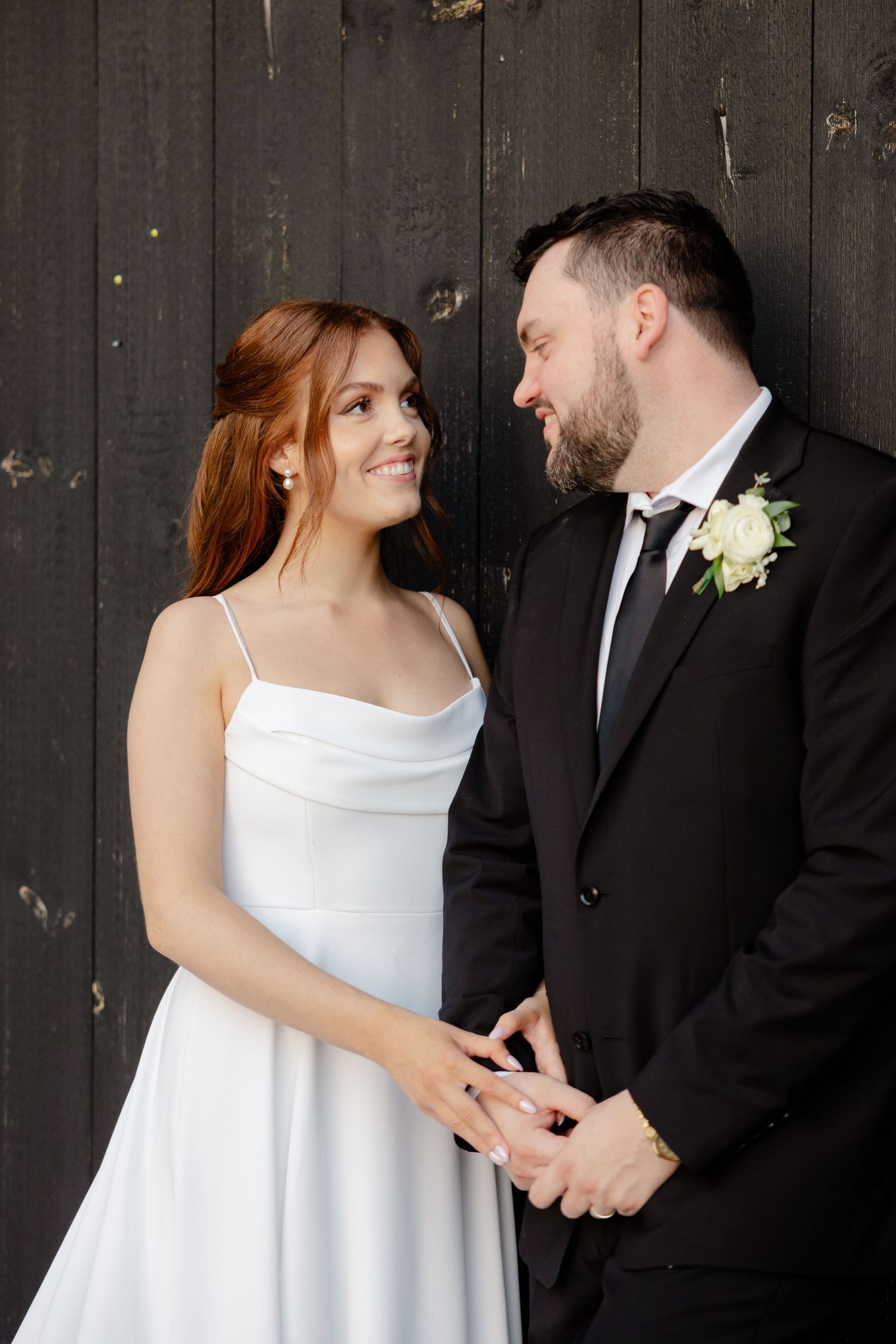 Close-up wedding portrait against dark wooden wall showing tender moment.