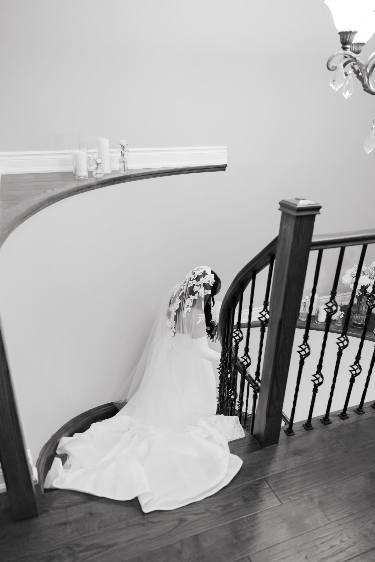 Dramatic black and white staircase photo showcasing wedding dress train and veil.