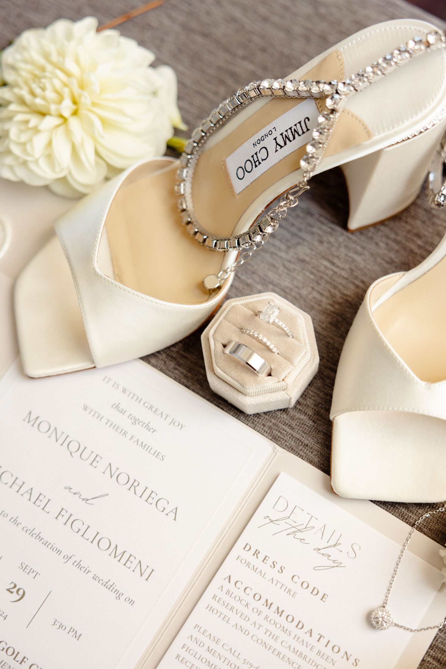 Close-up of bridal shoes and wedding invitations with floral accents and wax seal.