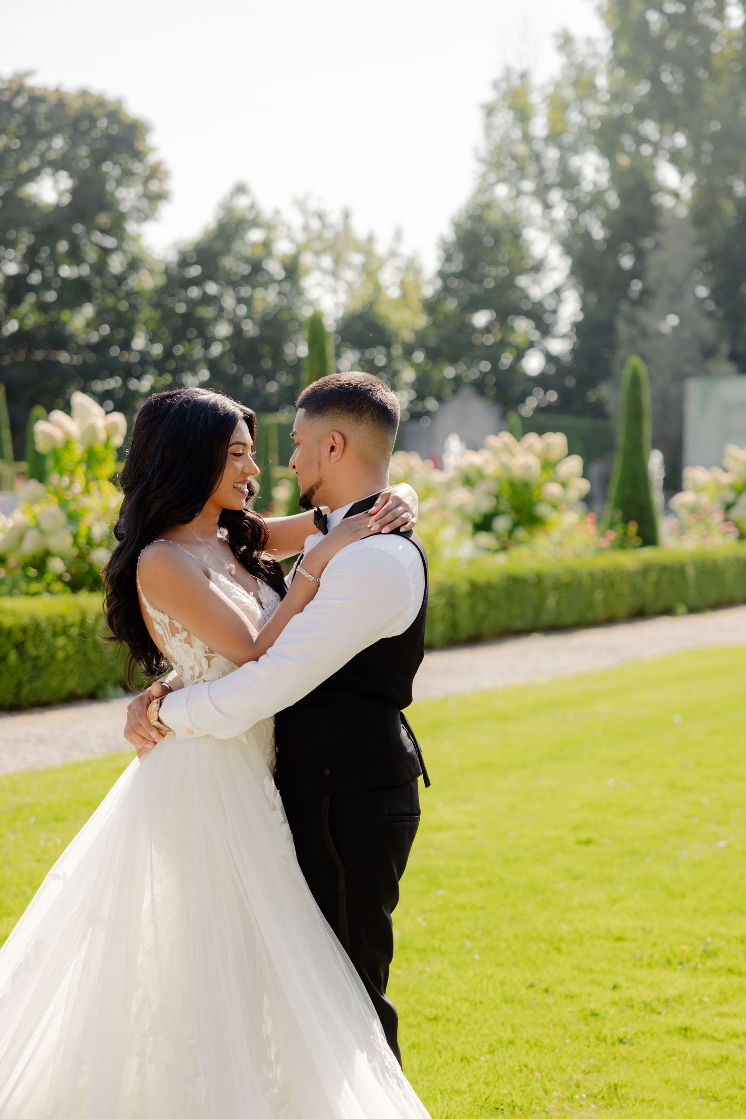 Wedding couple shares an intimate moment in a beautiful garden filled with flowers and greenery.