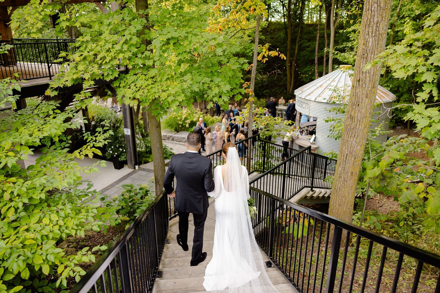 Wedding venue staircase surrounded by lush green foliage and black railings.
