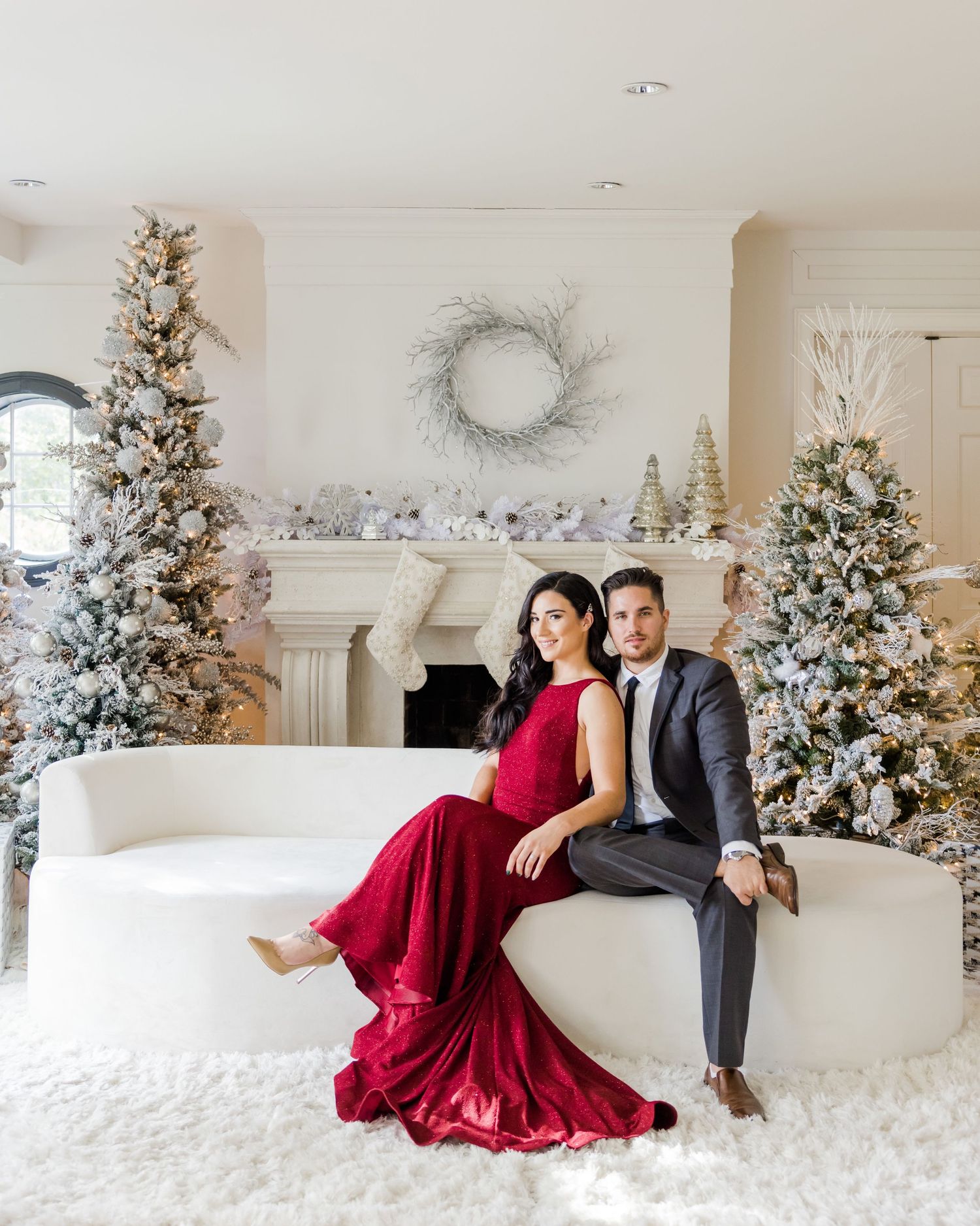 A glamorous holiday photo with a flowing red dress against white Christmas decor.