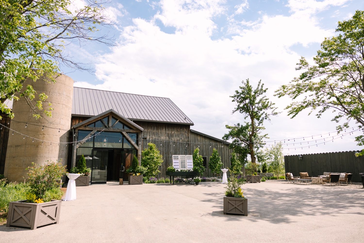 Modern rustic wedding venue exterior with stone facade and metal roof under blue sky.
