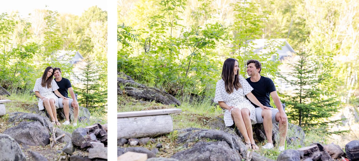 Couple sitting on rocky outcrop in nature during photo session with trees in background.