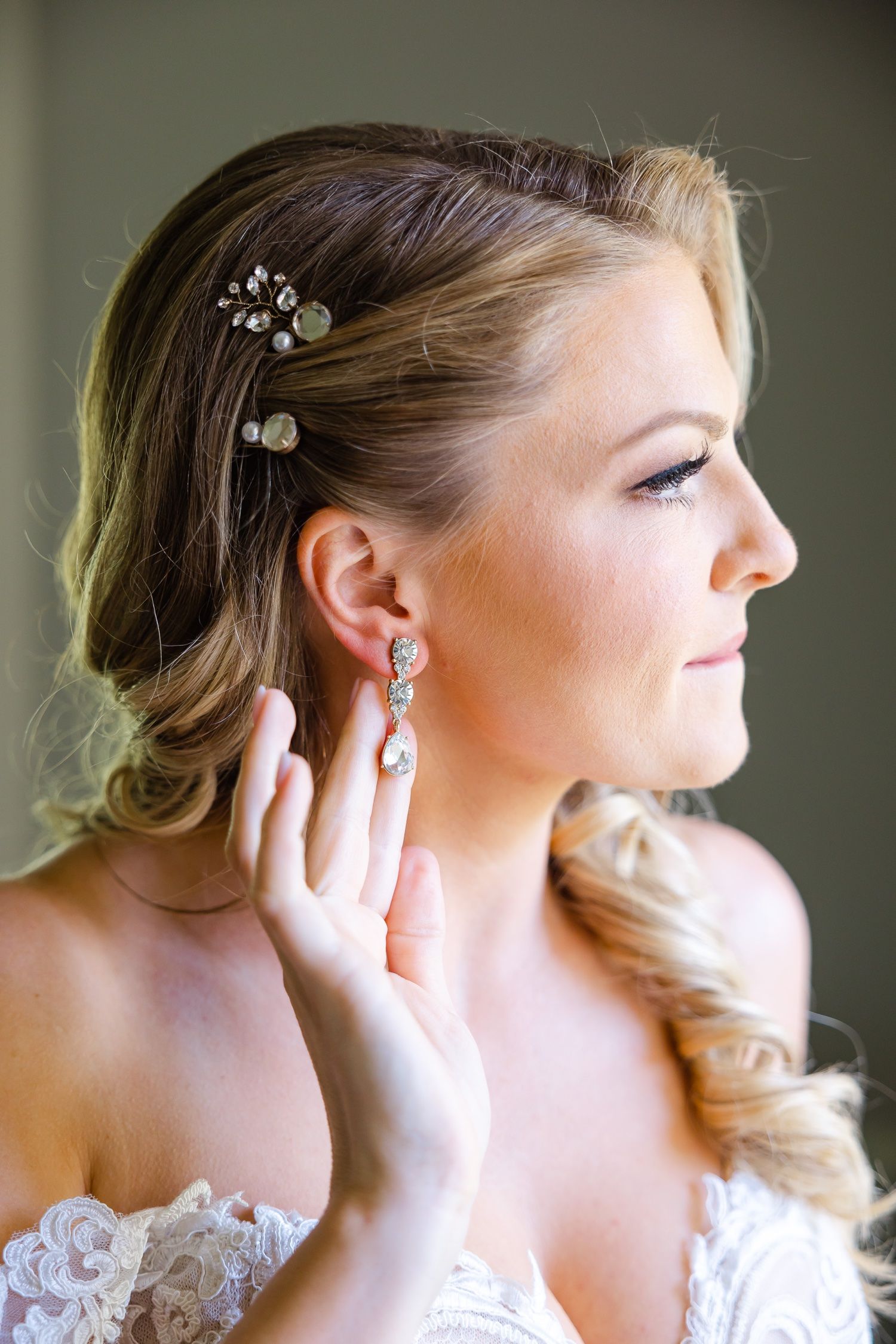 Close up of bridal hair accessory and earring details in soft lighting.