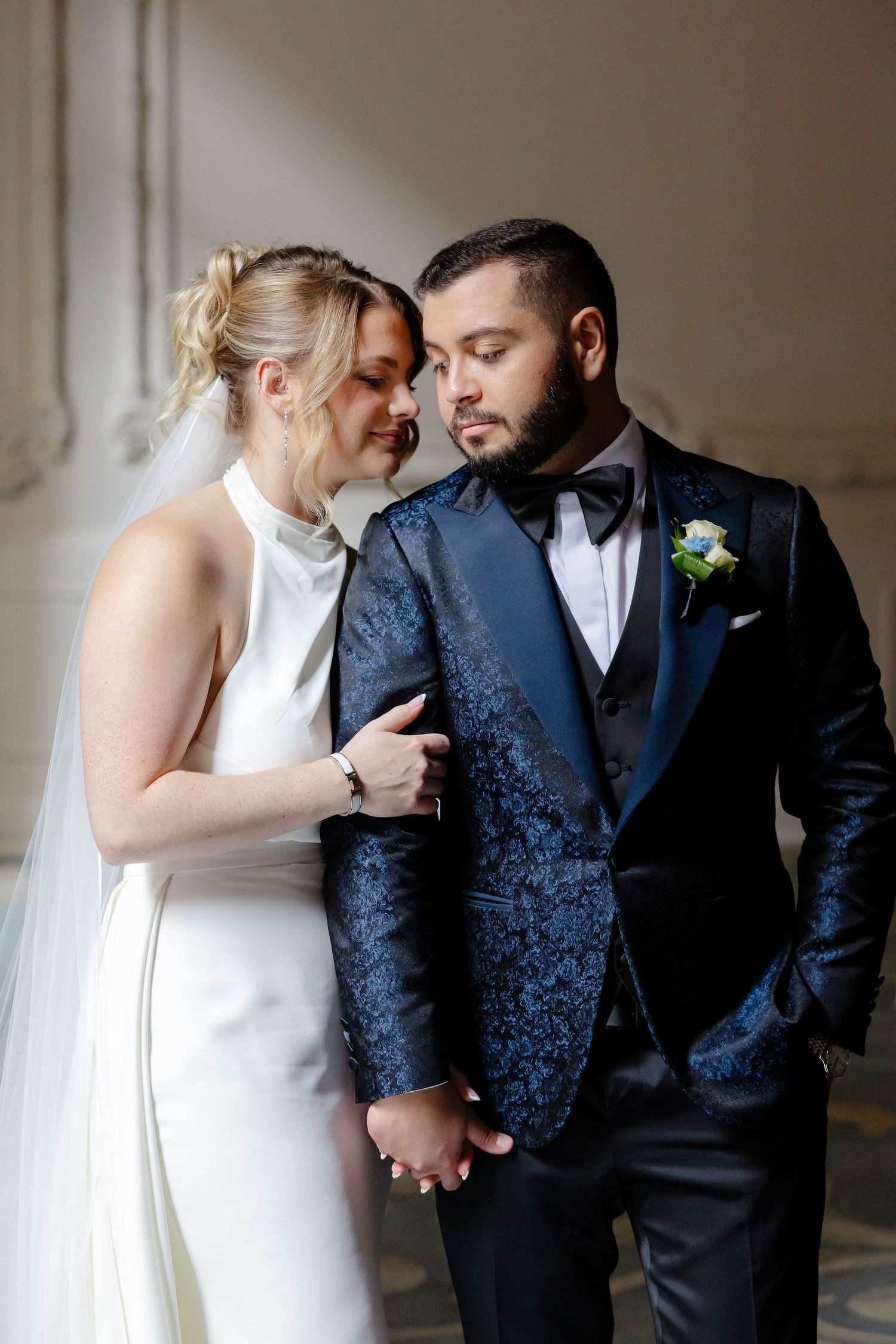 Intimate wedding portraits showing couple in formal attire sharing tender moments against neutral backdrop.