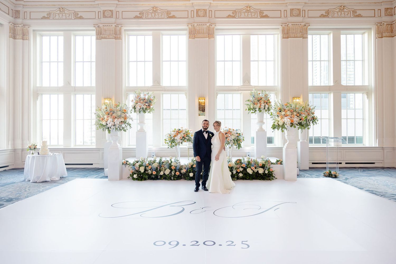 Elegant ballroom wedding venue with tall windows and floral arrangements.