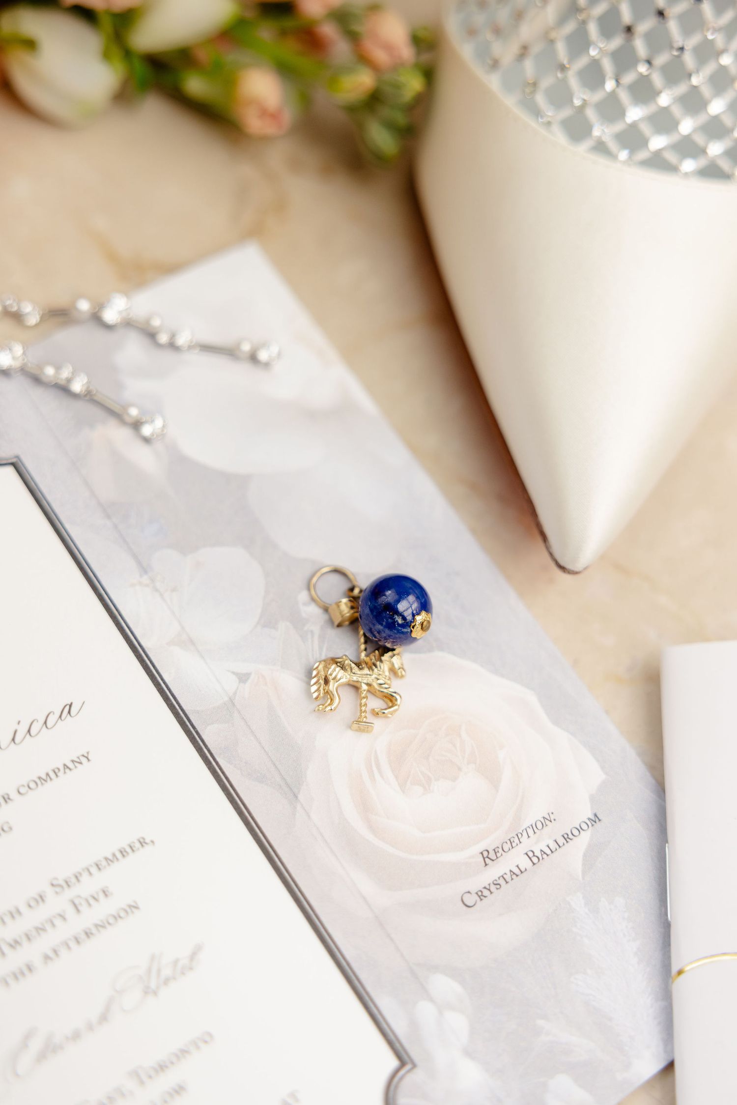 Elegant wedding details including white shoes, jewelry, and floral arrangements on a beige surface.