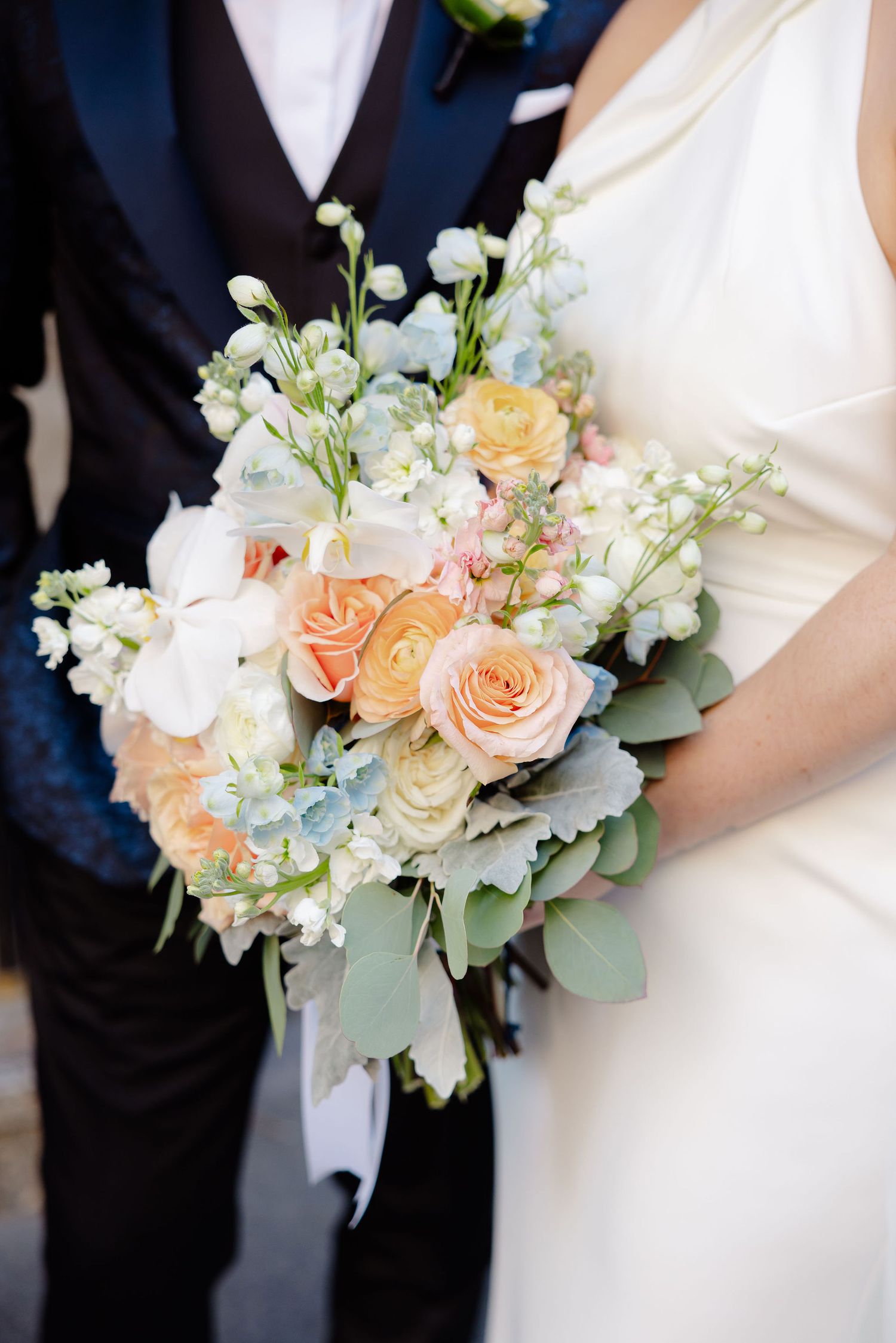 Close-up shots of an elegant bridal bouquet featuring peach roses, white flowers and greenery.