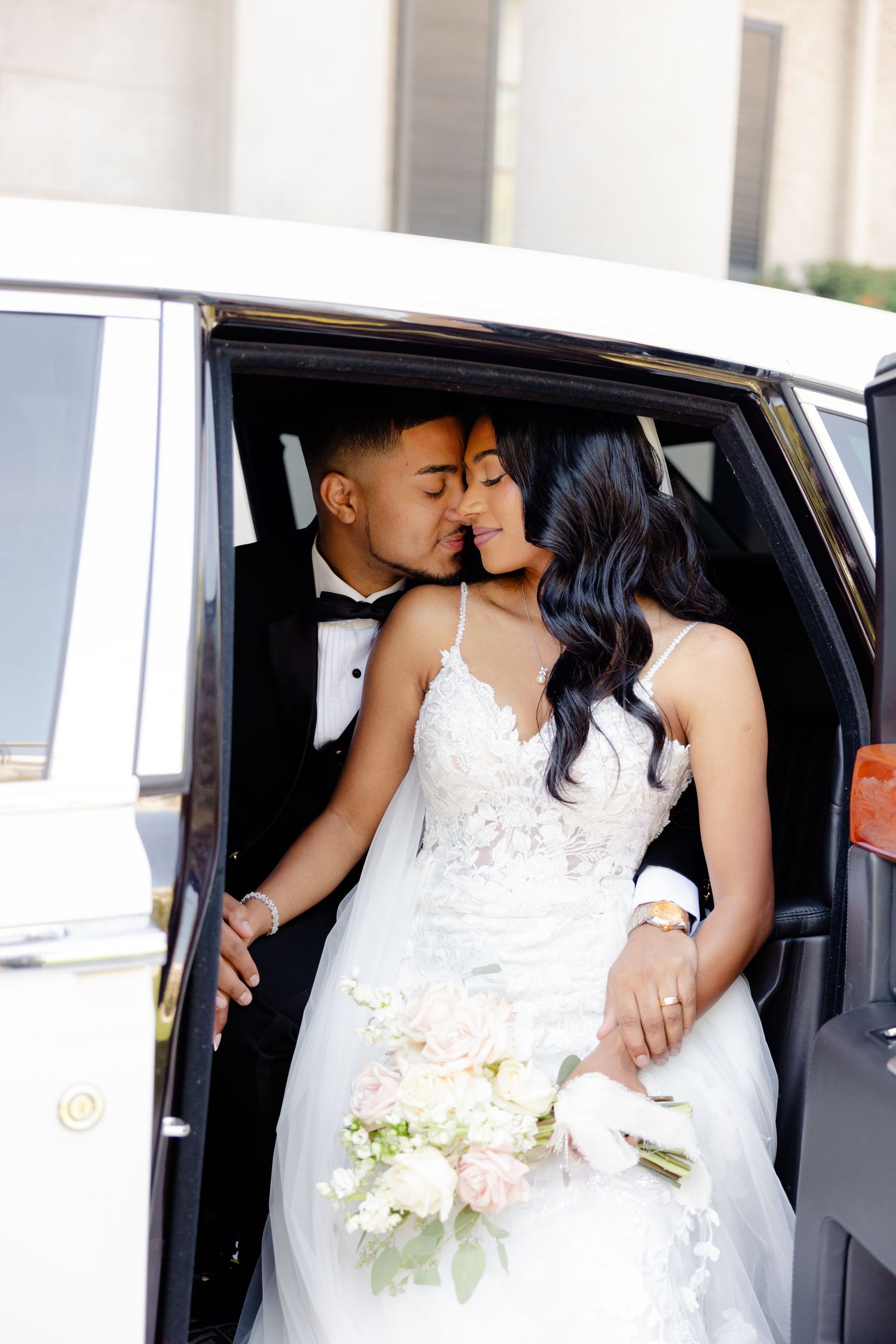 Romantic wedding photo of couple sharing a tender moment inside their luxury vehicle.