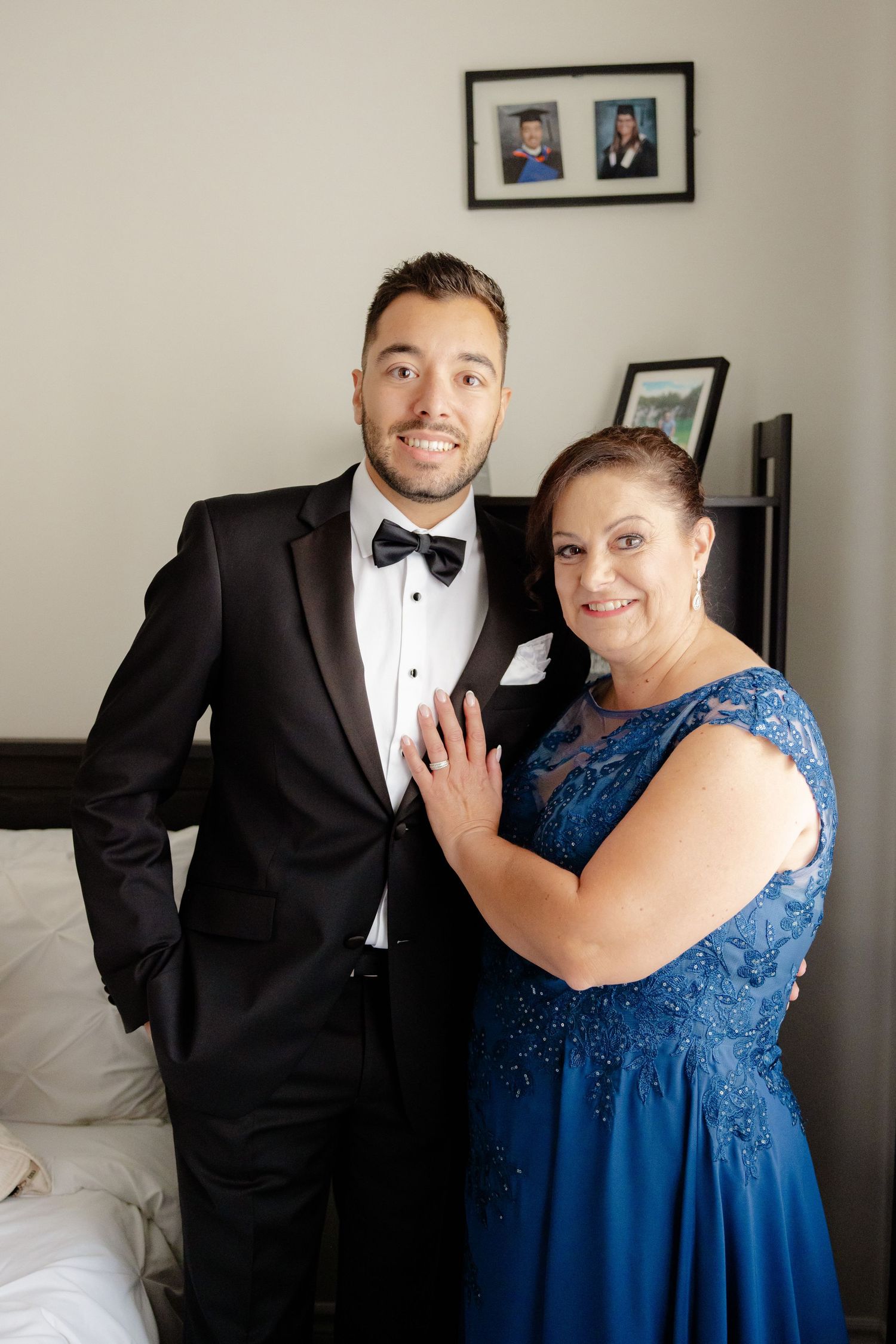 Wedding party member in tuxedo poses with guest in sparkly blue evening gown.