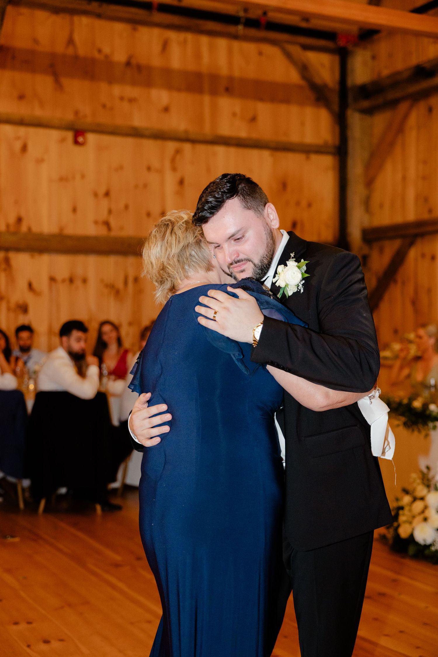An emotional dance moment between two people at a rustic barn wedding reception.