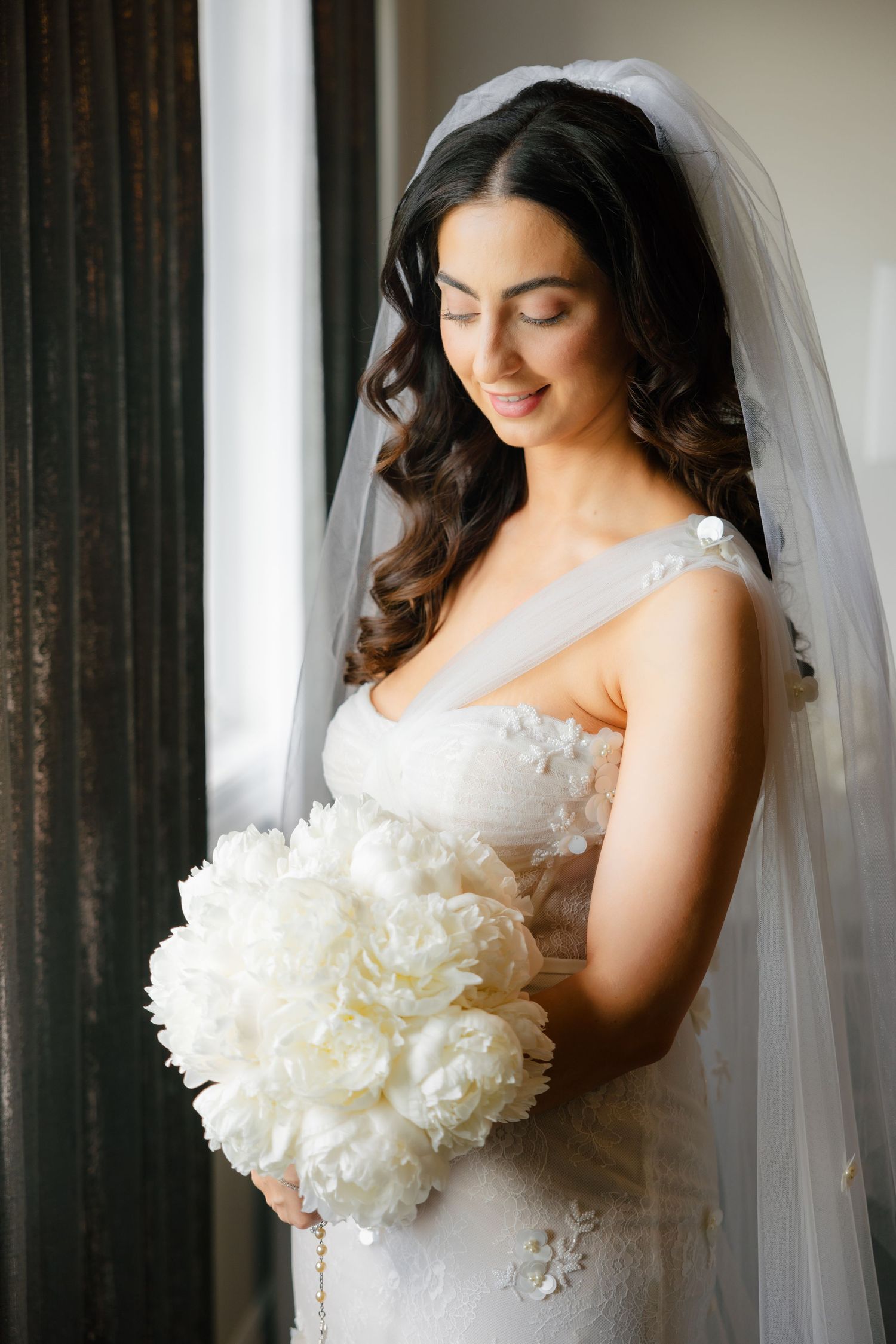 Serene bridal portrait with soft window lighting and dramatic white peony bouquet.