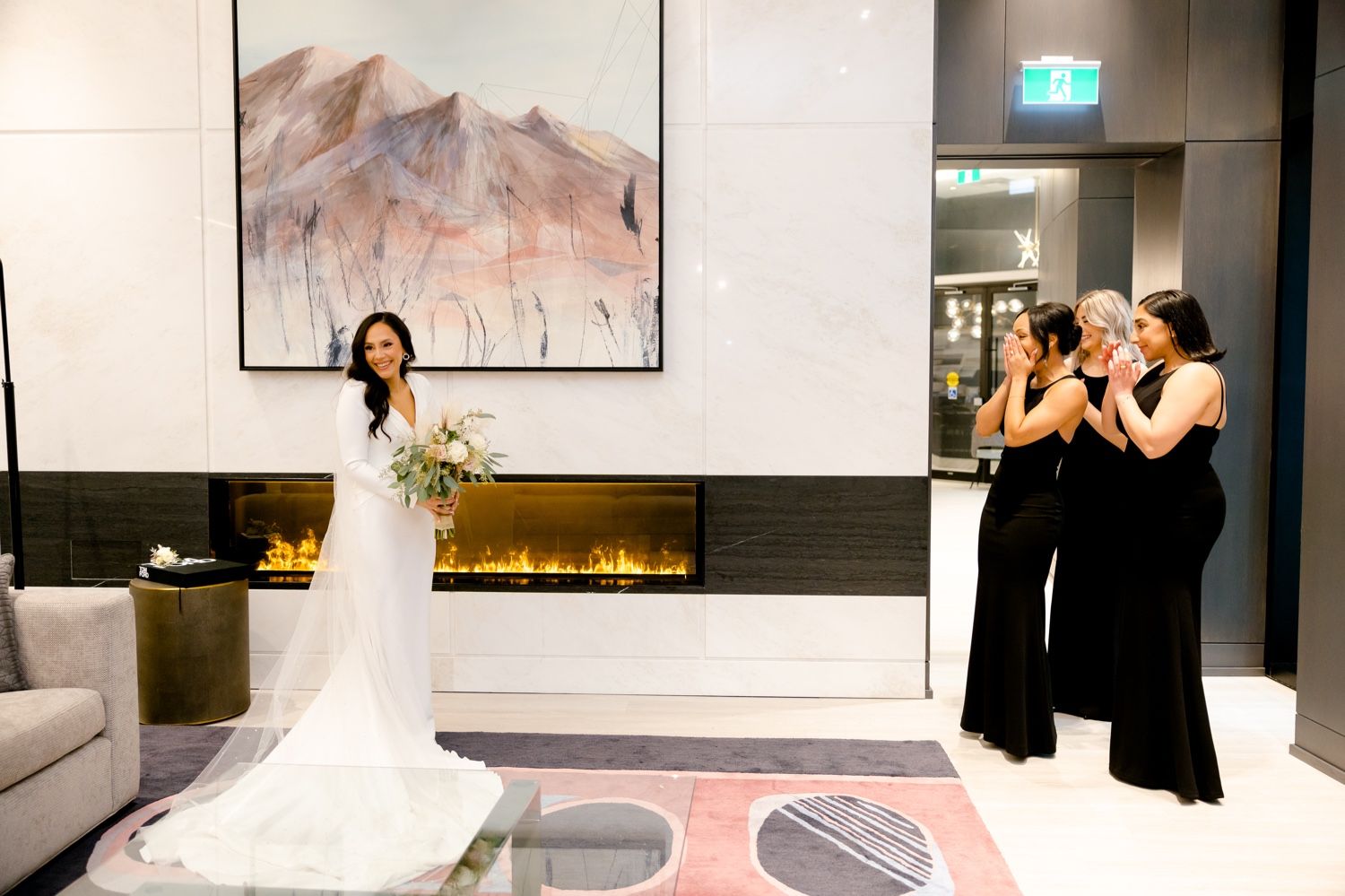 Emotional reveal moment between bride in white gown and wedding party in black dresses.